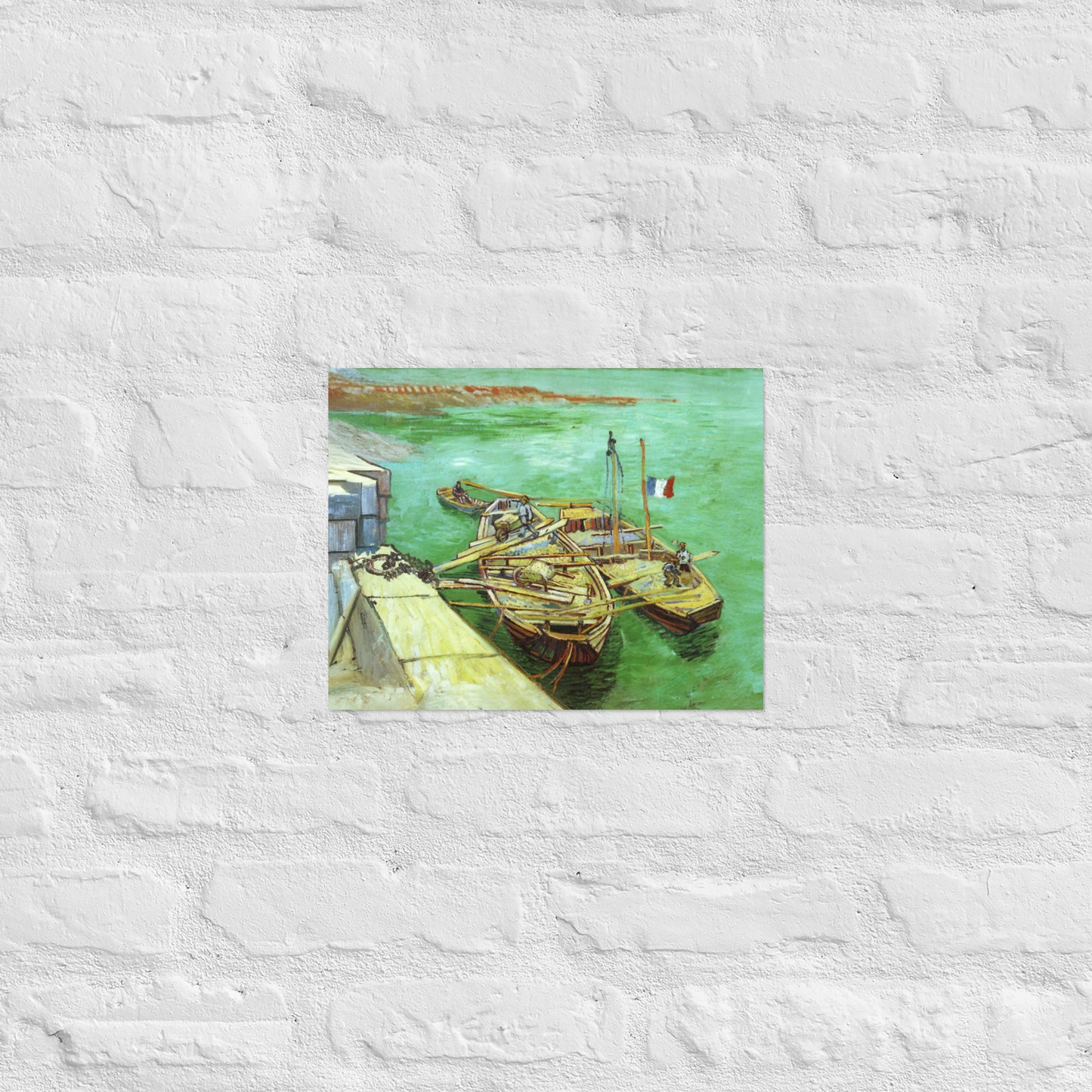 Van Gogh's 'Quay with Men Unloading Sand Barges' on a 11"x14" unframed poster print on a white brick wall.