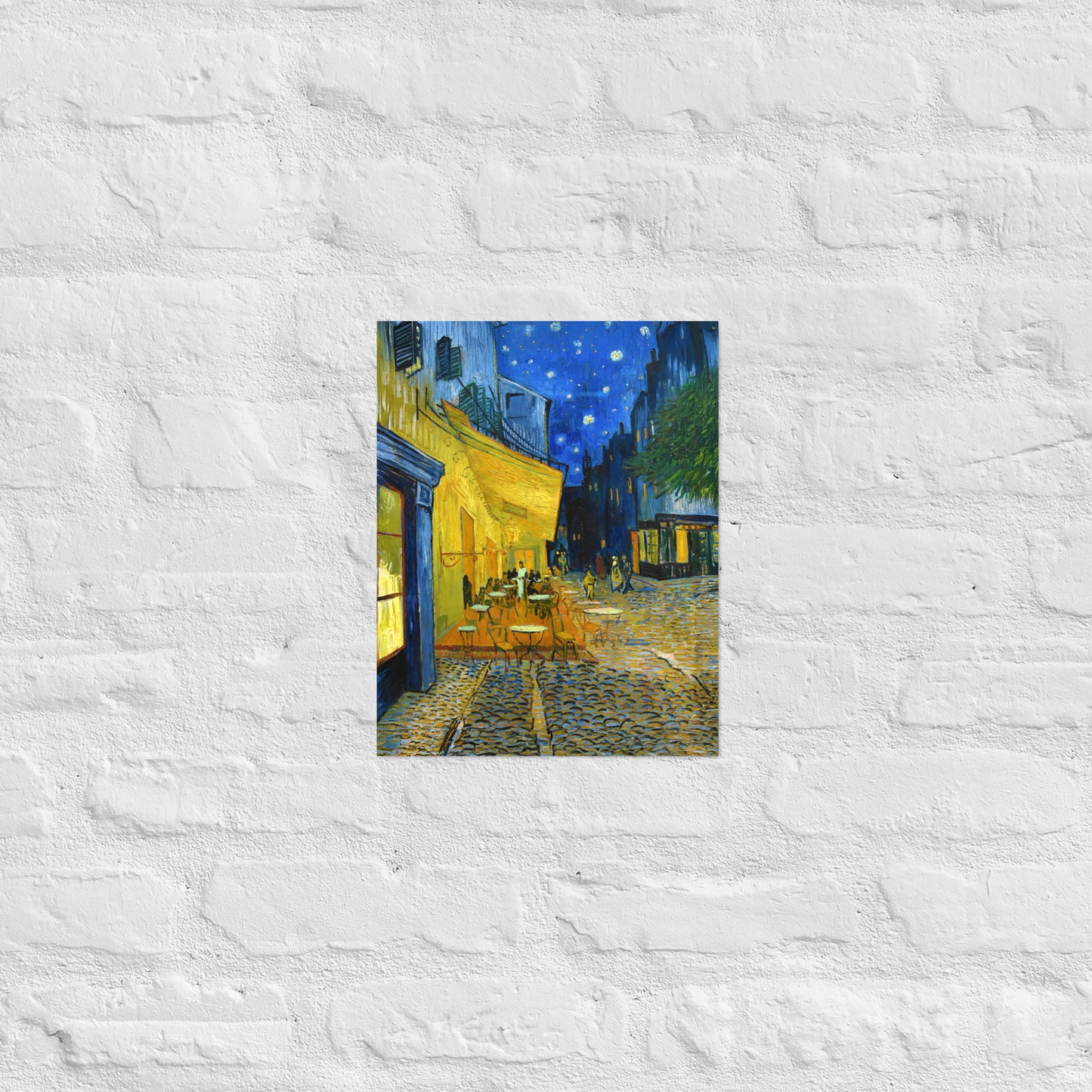 Van Gogh's 'Café Terrace at Night' on a 11"x14" unframed poster print on a white brick wall.
