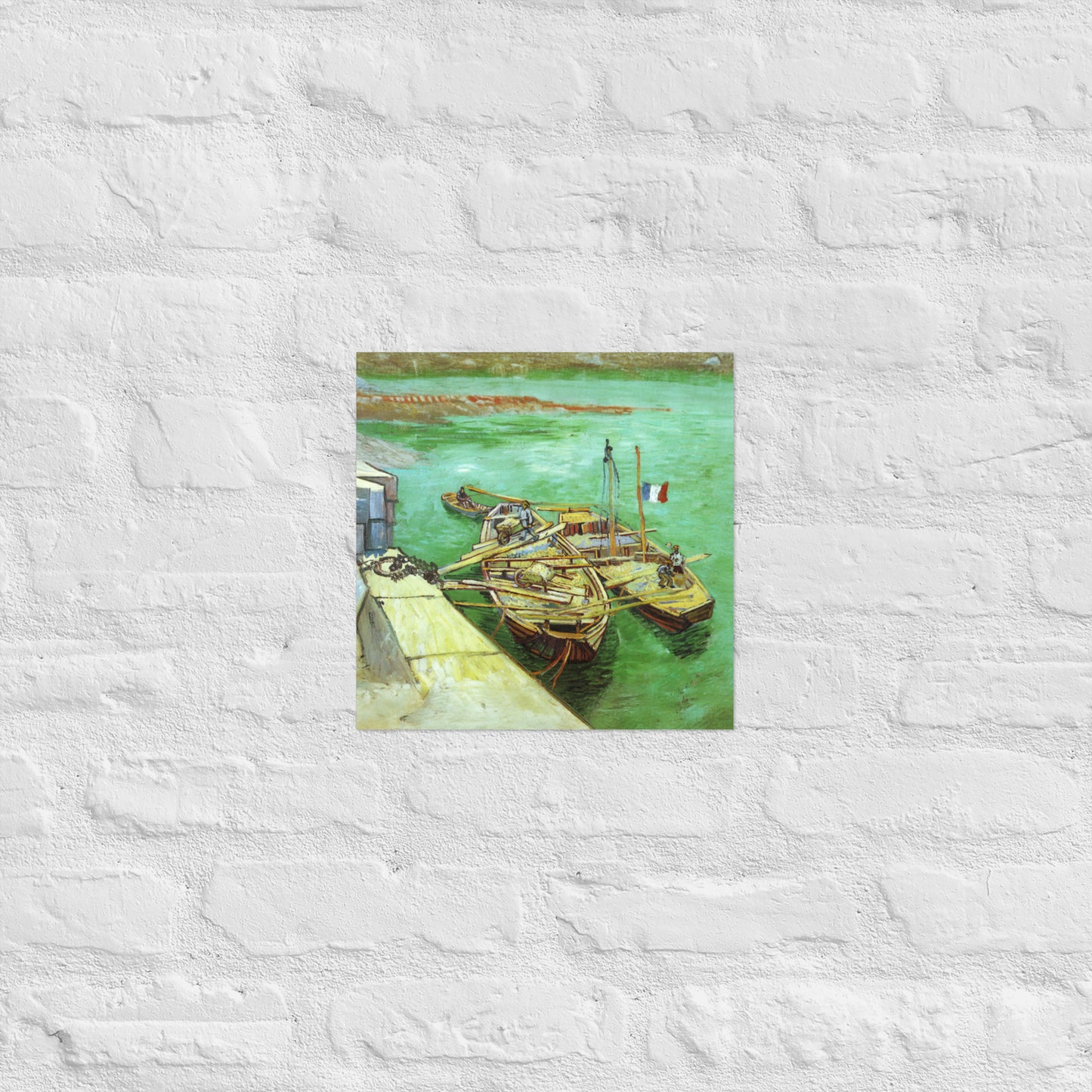 Van Gogh's 'Quay with Men Unloading Sand Barges' on a 12"x12" unframed poster print on a white brick wall.