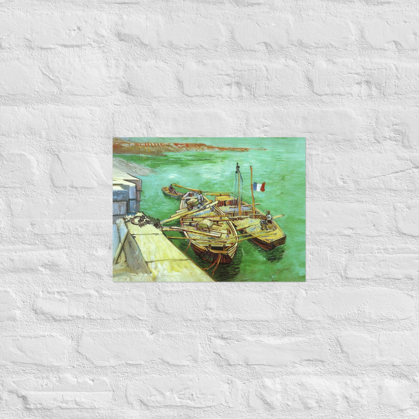 Van Gogh's 'Quay with Men Unloading Sand Barges' on a 12"x16" unframed poster print on a white brick wall.