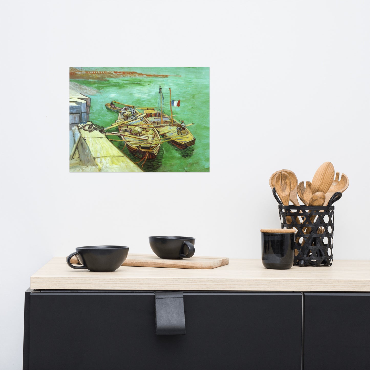 Van Gogh's 'Quay with Men Unloading Sand Barges' on a 12"x16" unframed poster print on a white wall above a kitchen counter with cooking supplies.