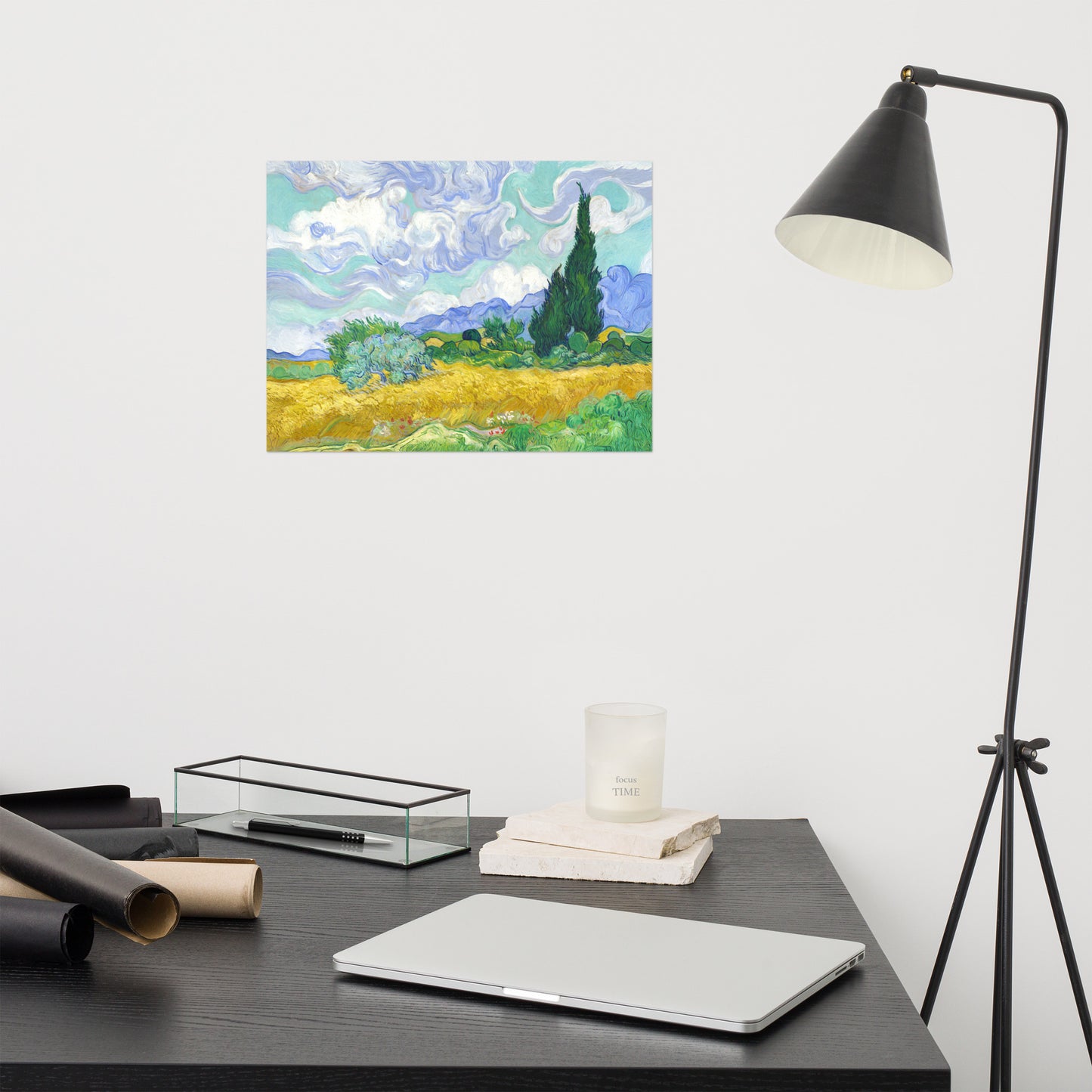 Van Gogh's 'Wheat Field with Cypresses' on a 12"x16" unframed poster print on a white wall above a modern office desk, lamp, and assorted desk items.