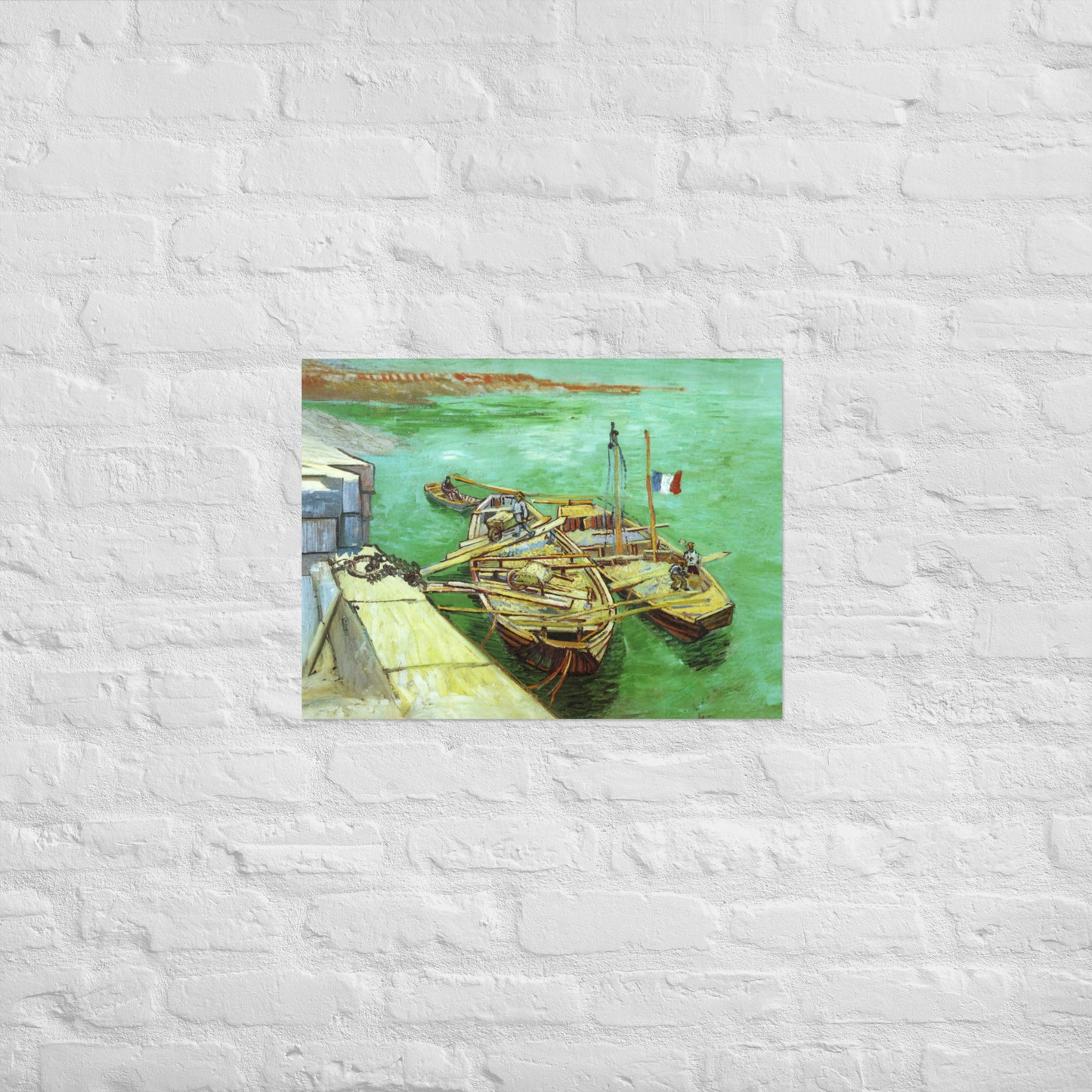 Van Gogh's 'Quay with Men Unloading Sand Barges' on a 18"x24" unframed poster print on a white brick wall.