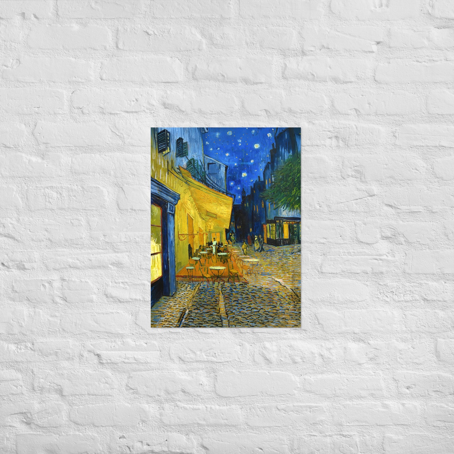 Van Gogh's 'Café Terrace at Night' on a 18"x24" unframed poster print on a white brick wall.