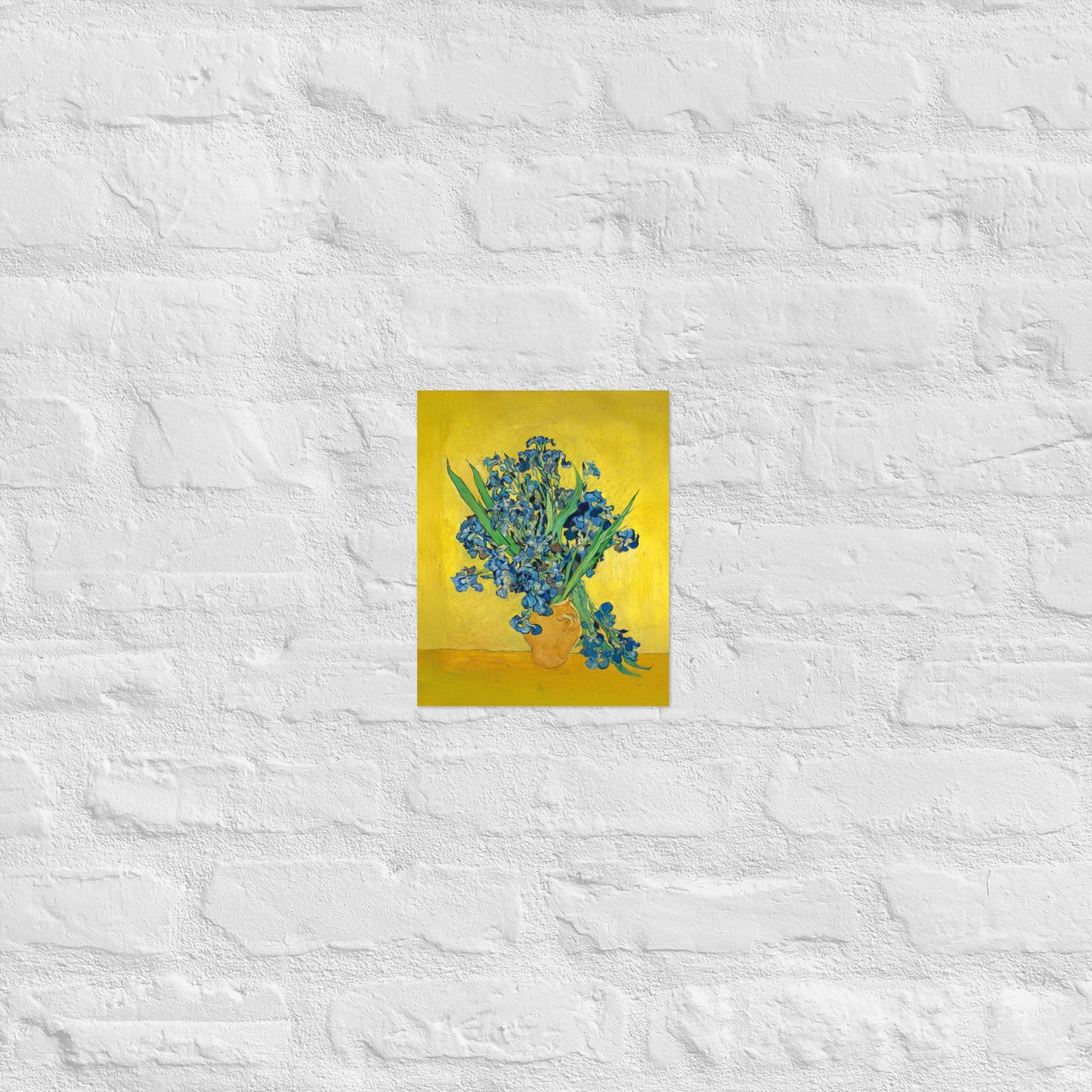 Van Gogh's 'Vase with Irises Against a Yellow Background' on a 8"x10" unframed poster print on a white brick wall.