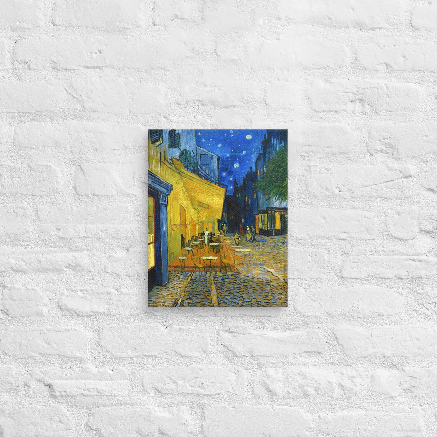Van Gogh's 'Café Terrace at Night' on a 11"x14" unframed canvas print on a white brick wall.