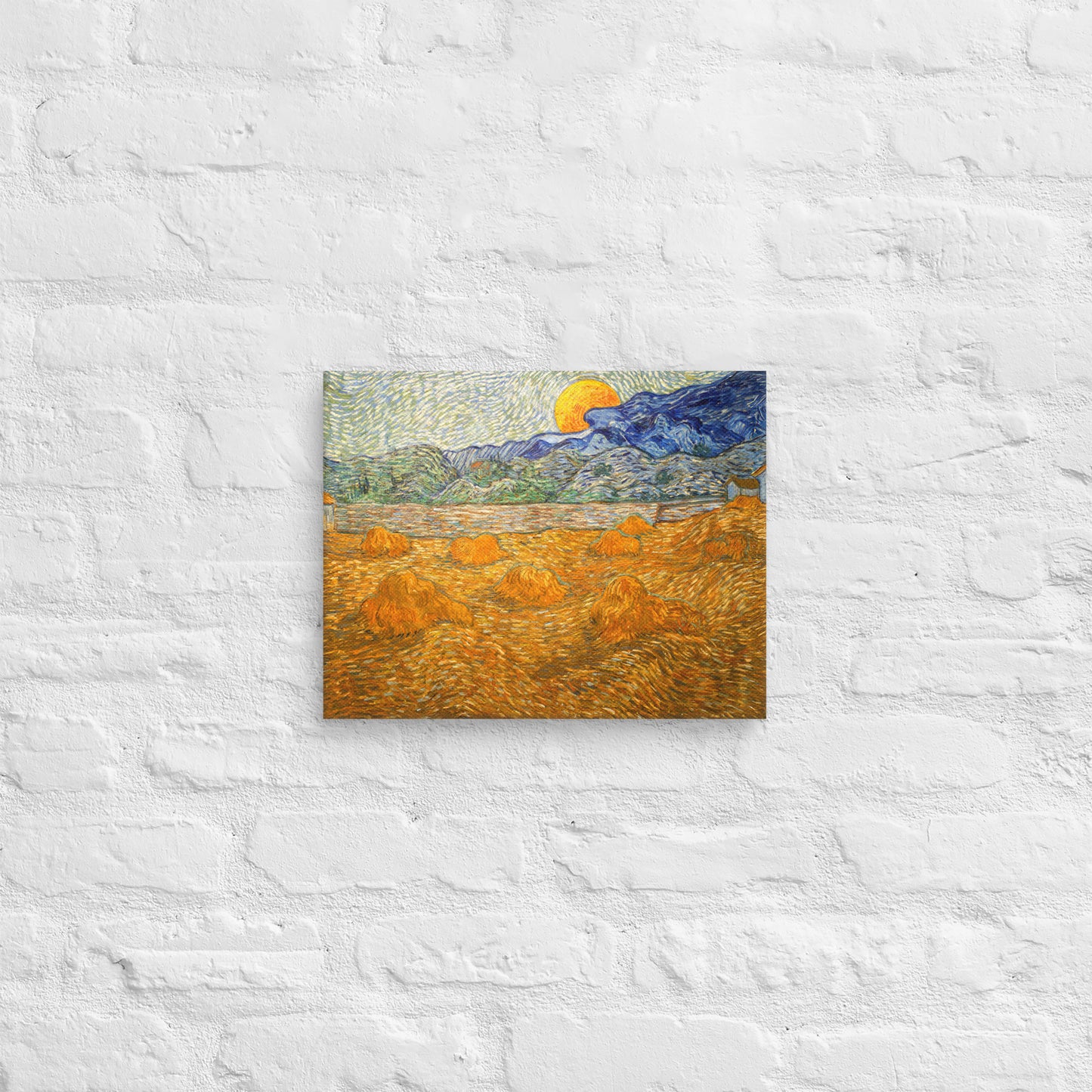 Van Gogh's 'Landscape with Wheat Sheaves and Rising Moon' on a 11"x14" unframed canvas print on a white brick wall.