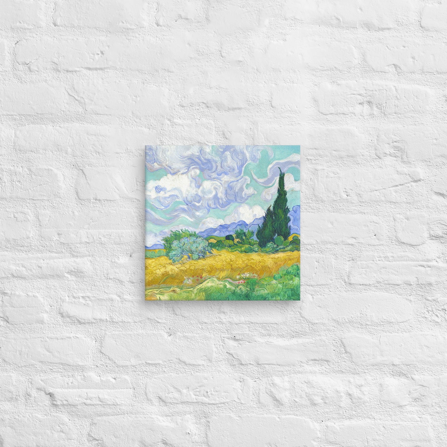 Van Gogh's 'Wheat Field with Cypresses' on a 12"x12" unframed canvas print on a white brick wall.