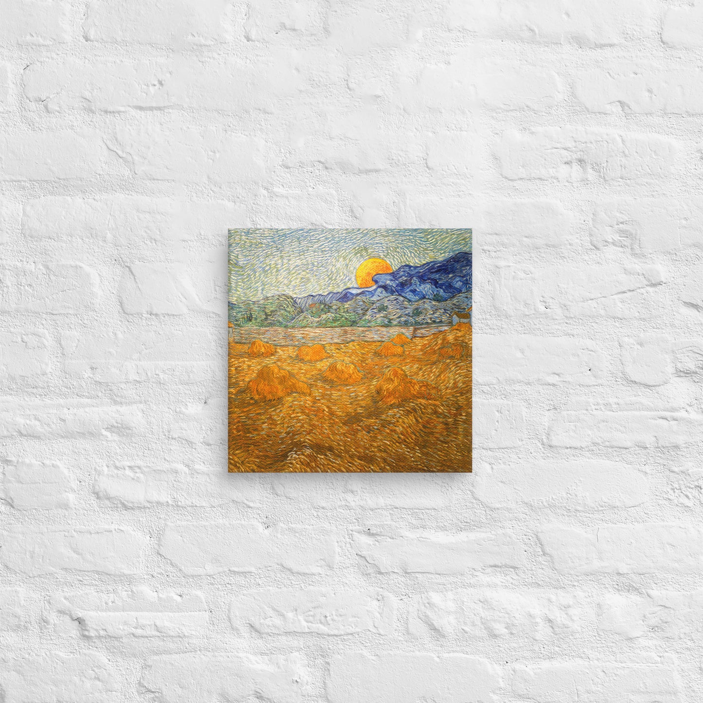Van Gogh's 'Landscape with Wheat Sheaves and Rising Moon' on a 12"x12" unframed canvas print on a white brick wall.