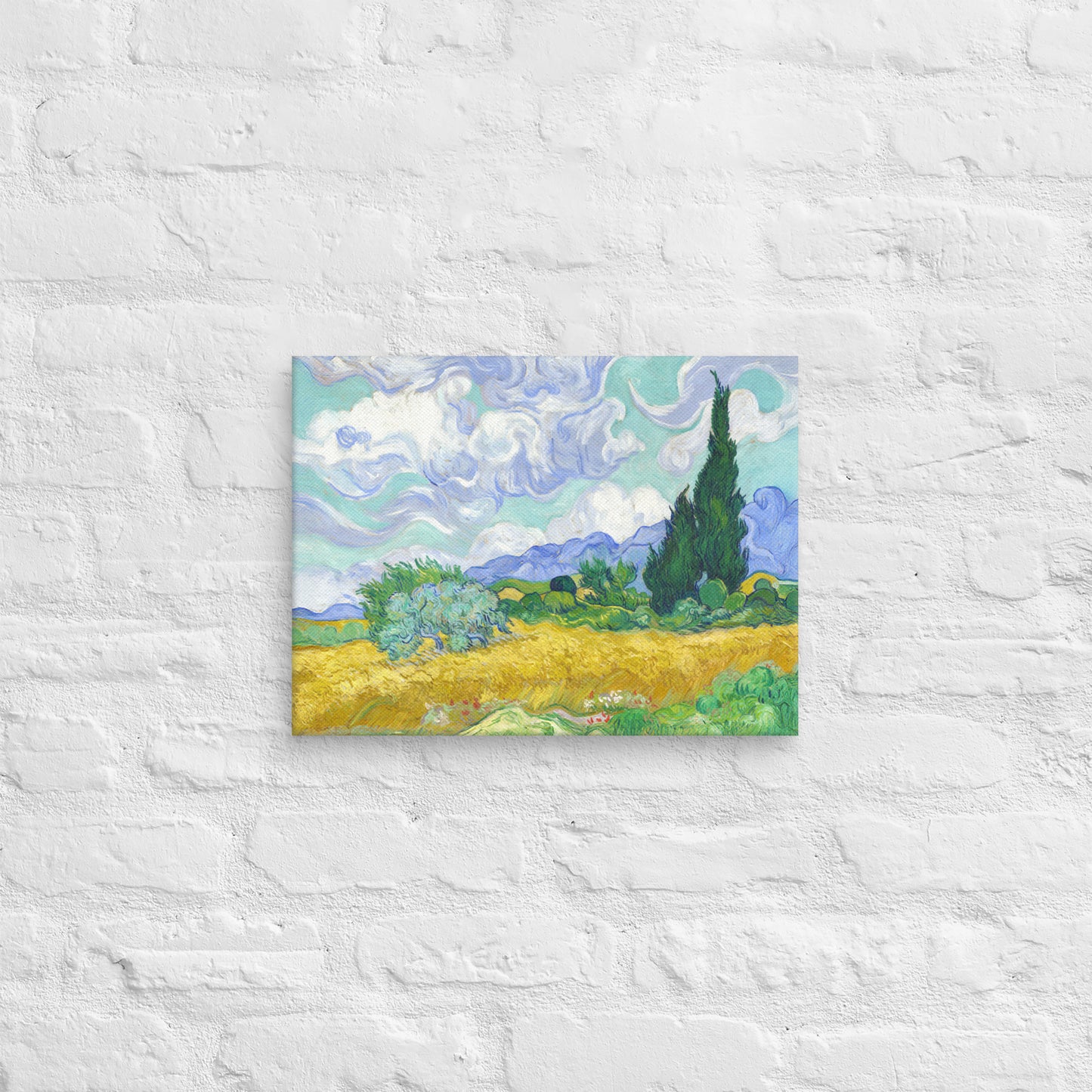 Van Gogh's 'Wheat Field with Cypresses' on a 12"x16" unframed canvas print on a white brick wall.