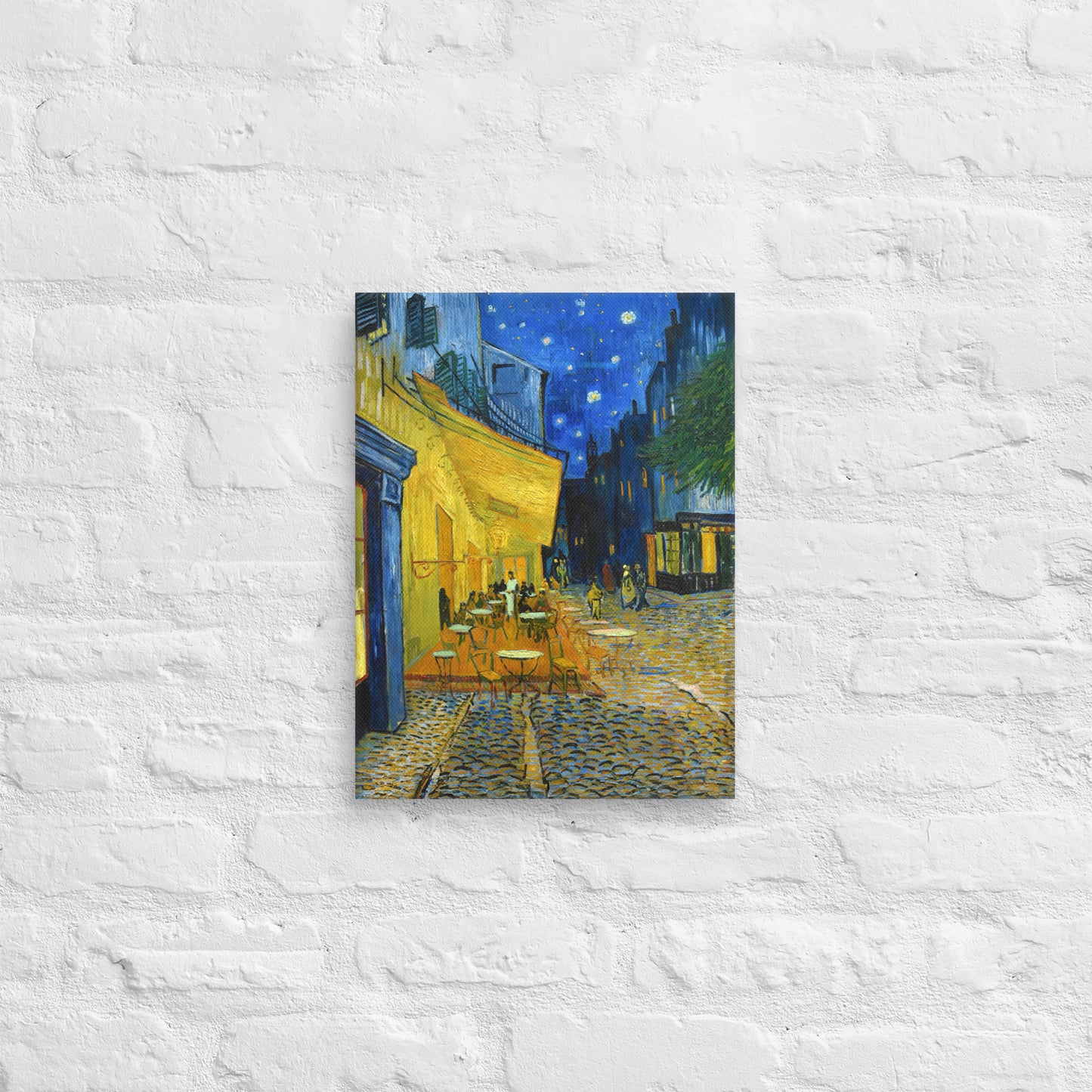Van Gogh's 'Café Terrace at Night' on a 12"x16" unframed canvas print on a white brick wall.