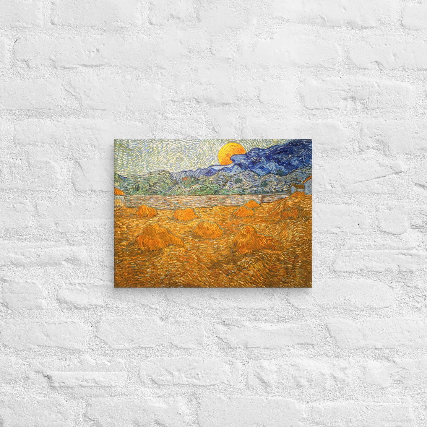 Van Gogh's 'Landscape with Wheat Sheaves and Rising Moon' on a 12"x16" unframed canvas print on a white brick wall.