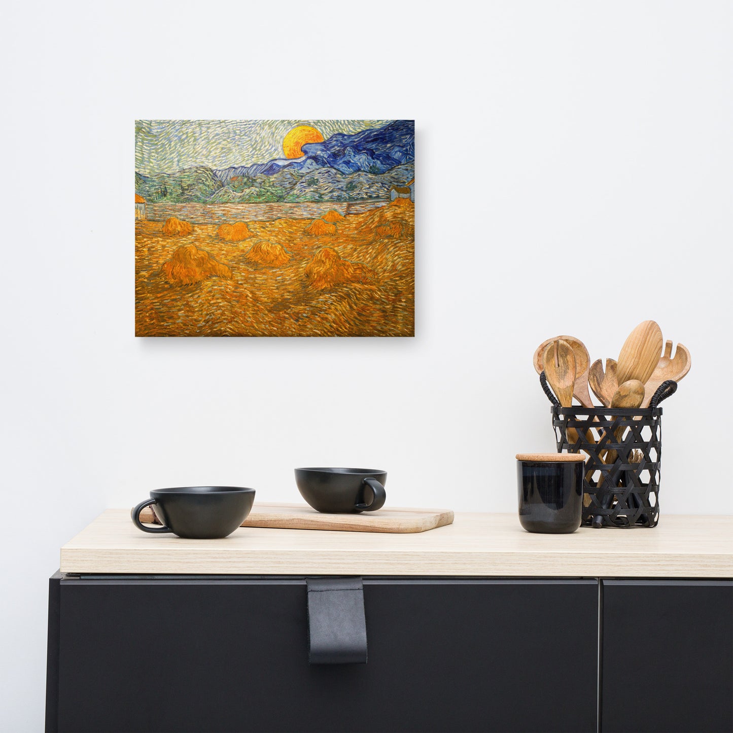 Van Gogh's 'Landscape with Wheat Sheaves and Rising Moon' on a 12"x16" unframed canvas print on a white wall above a kitchen counter with cooking supplies.