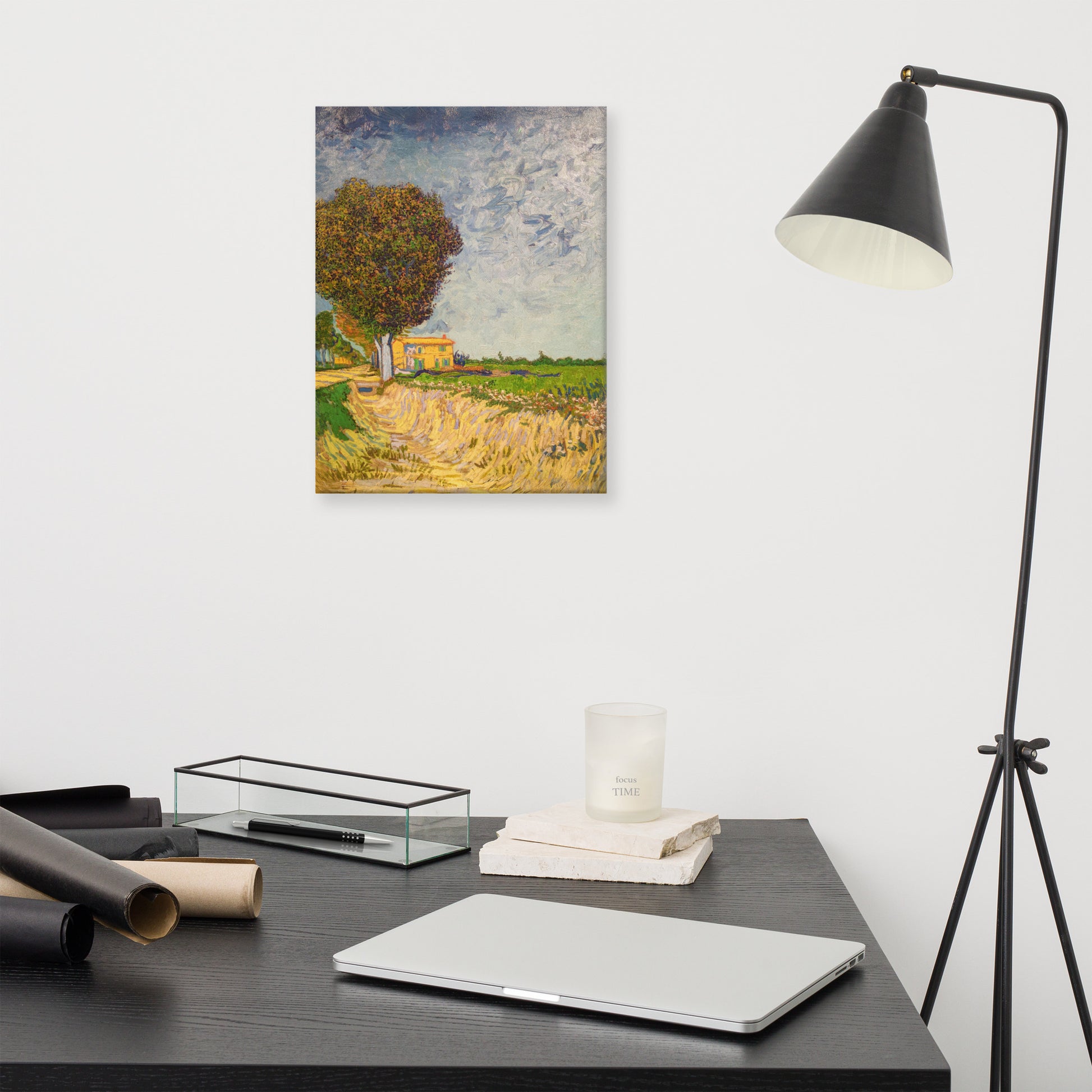 Van Gogh's 'A Lane near Arles' on a 12"x16" unframed canvas print on a white wall above a modern office desk, lamp, and assorted desk items.