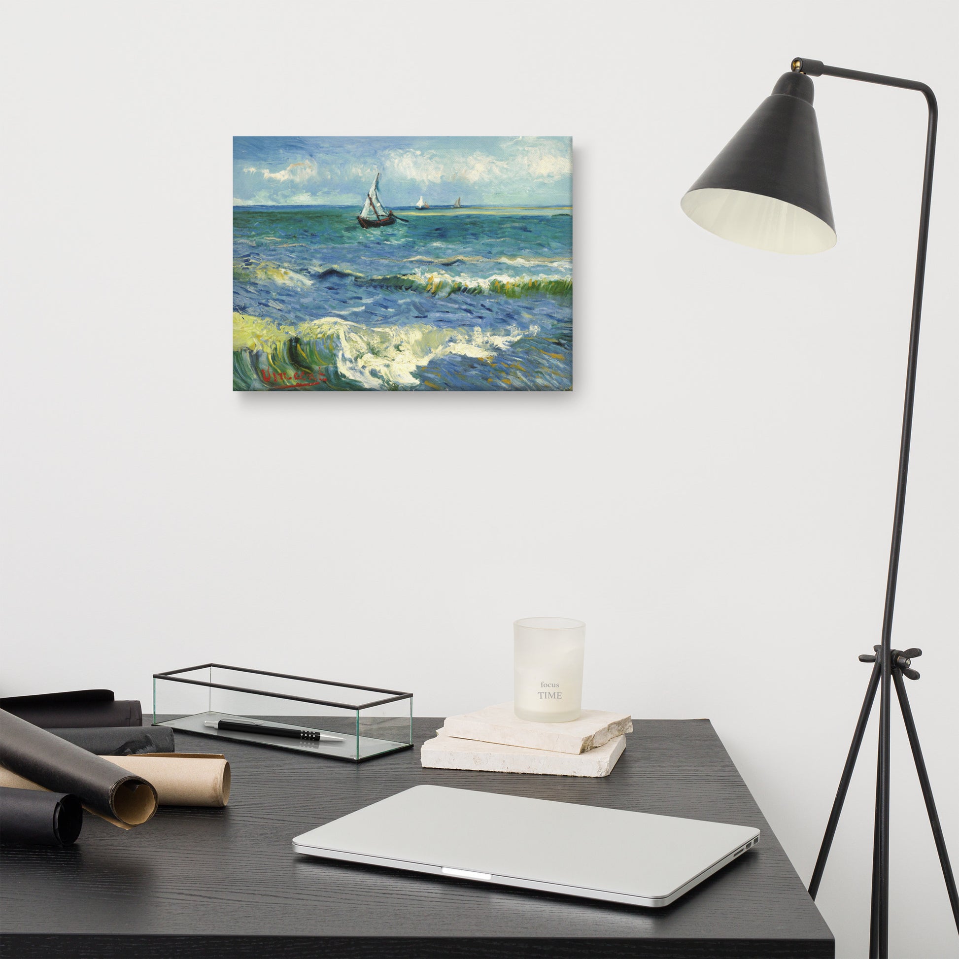 Van Gogh's 'The Sea at Les Saintes-Maries-de-la-Mer' on a 12"x16" unframed canvas print on a white wall above a modern office desk, lamp, and assorted desk items.
