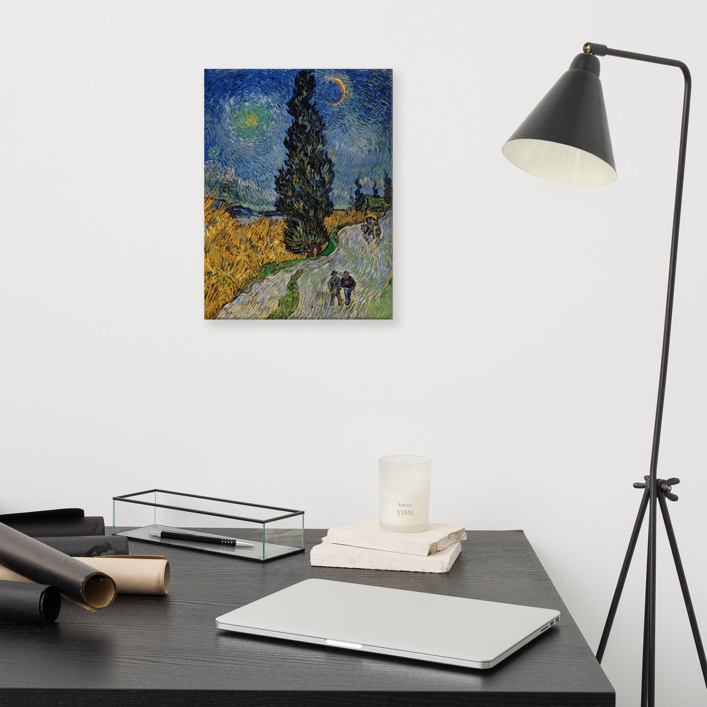 Van Gogh's 'Road with Cypress and Star' on a 12"x16" unframed canvas print on a white wall above a modern office desk, lamp, and assorted desk items.