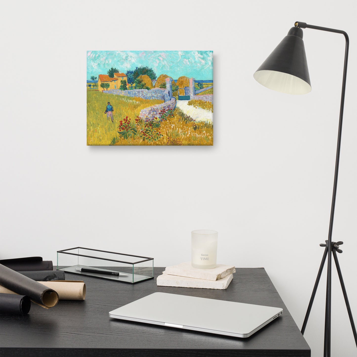 Van Gogh's 'Farmhouse in Provence' on a 12"x16" unframed canvas print on a white wall above a modern office desk, lamp, and assorted desk items.