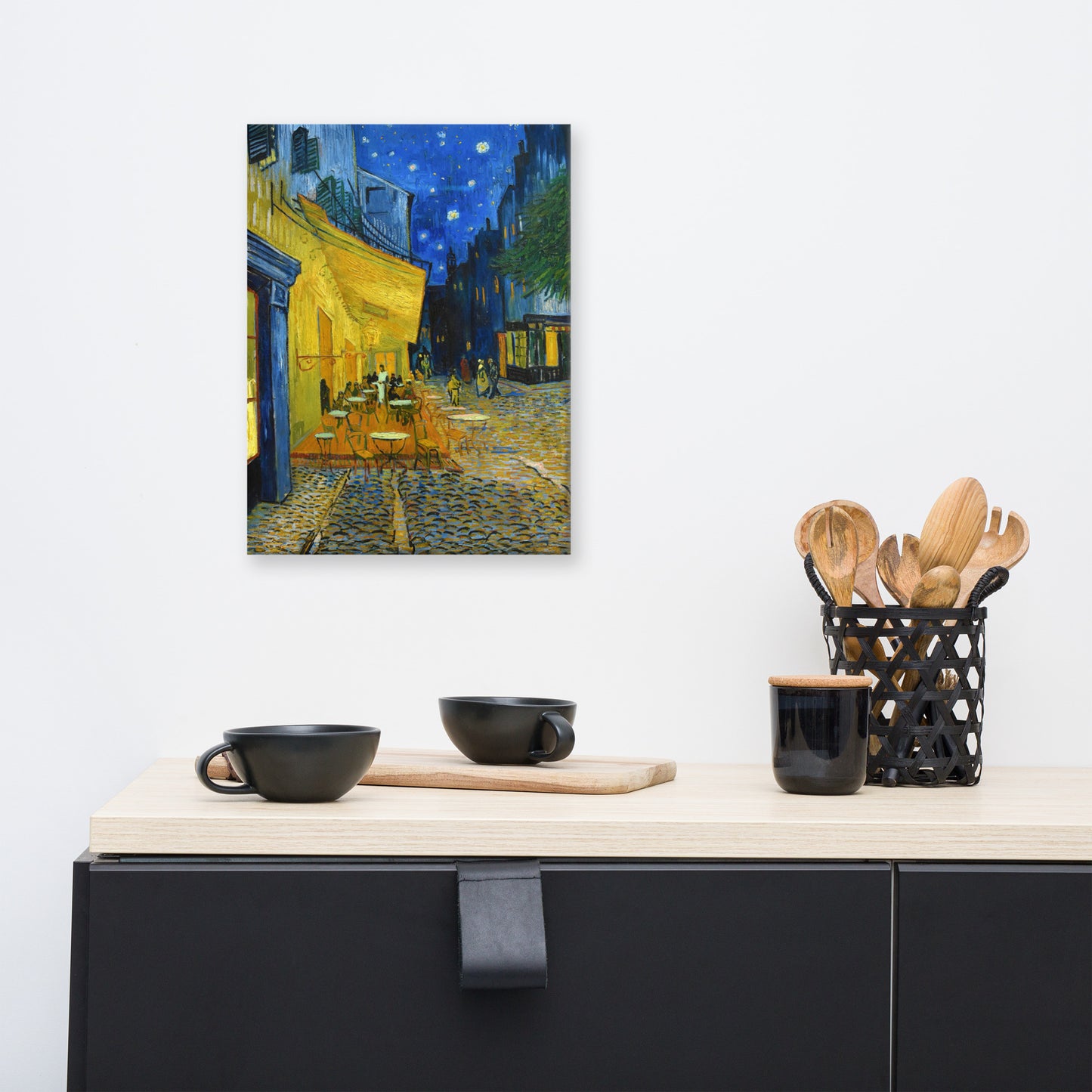 Van Gogh's 'Café Terrace at Night' on a 12"x16" unframed canvas print on a white wall above a kitchen counter with cooking supplies.