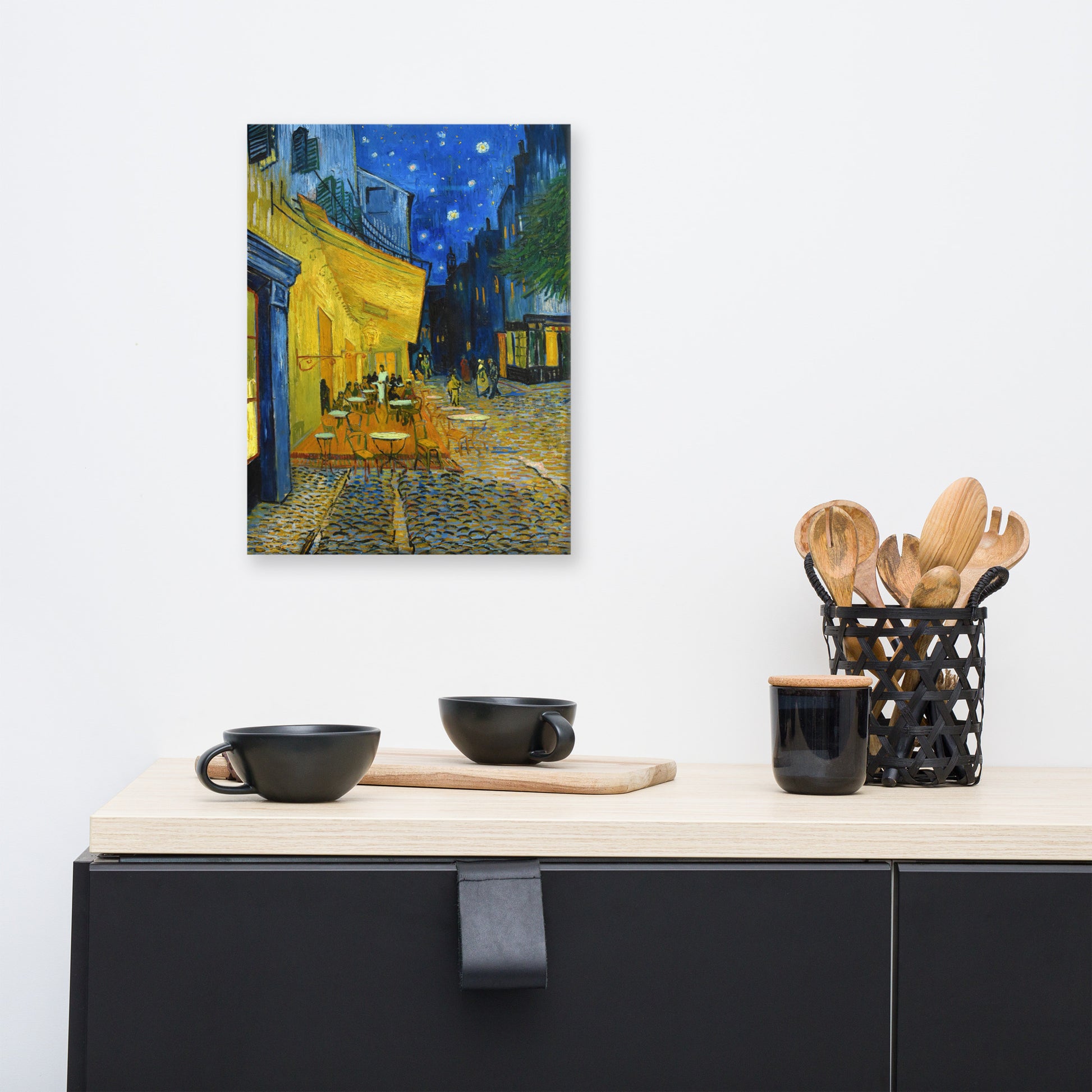 Van Gogh's 'Café Terrace at Night' on a 12"x16" unframed canvas print on a white wall above a kitchen counter with cooking supplies.