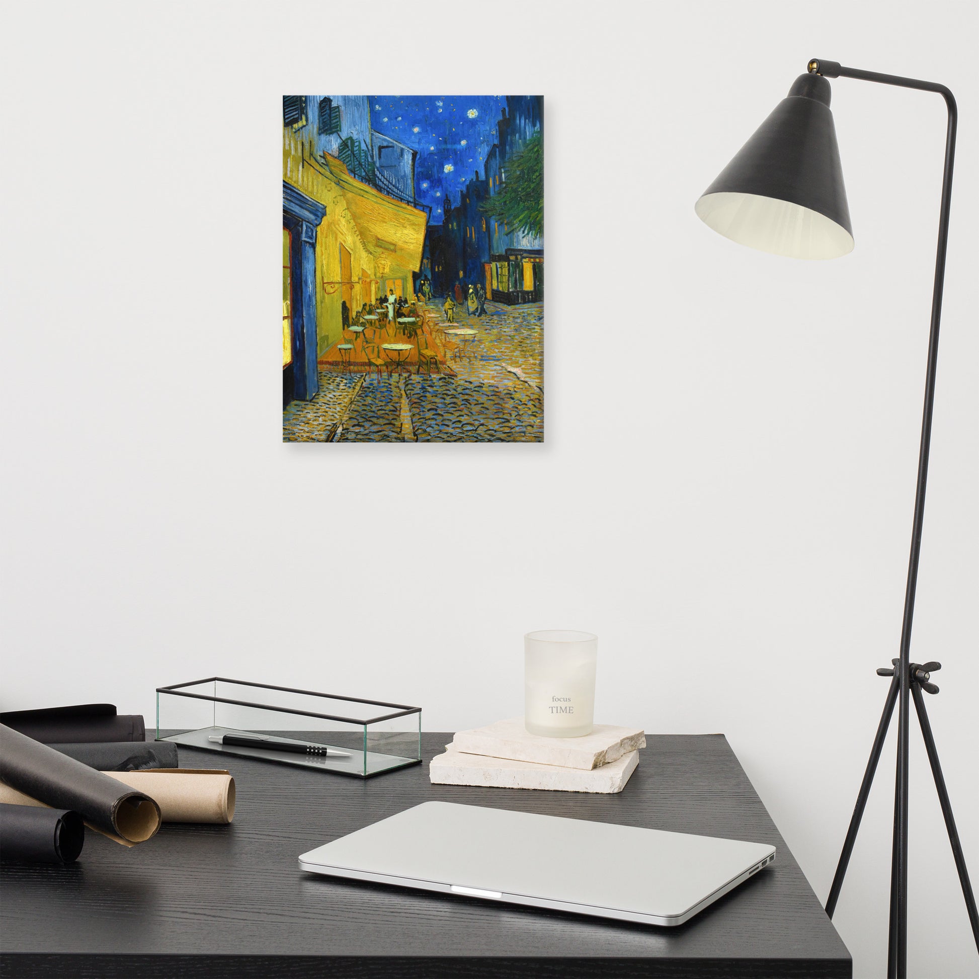 Van Gogh's 'Café Terrace at Night' on a 12"x16" unframed canvas print on a white wall above a modern office desk, lamp, and assorted desk items.