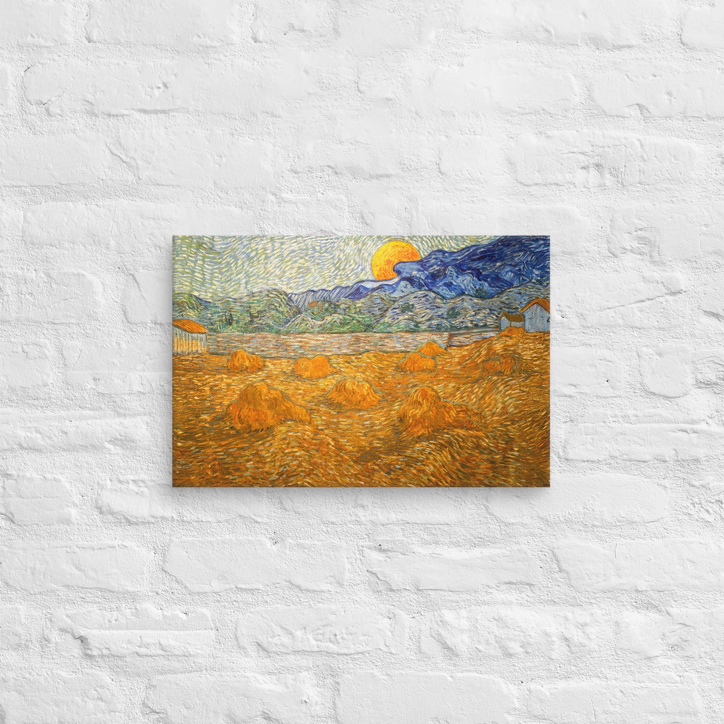 Van Gogh's 'Landscape with Wheat Sheaves and Rising Moon' on a 12"x18" unframed canvas print on a white brick wall.