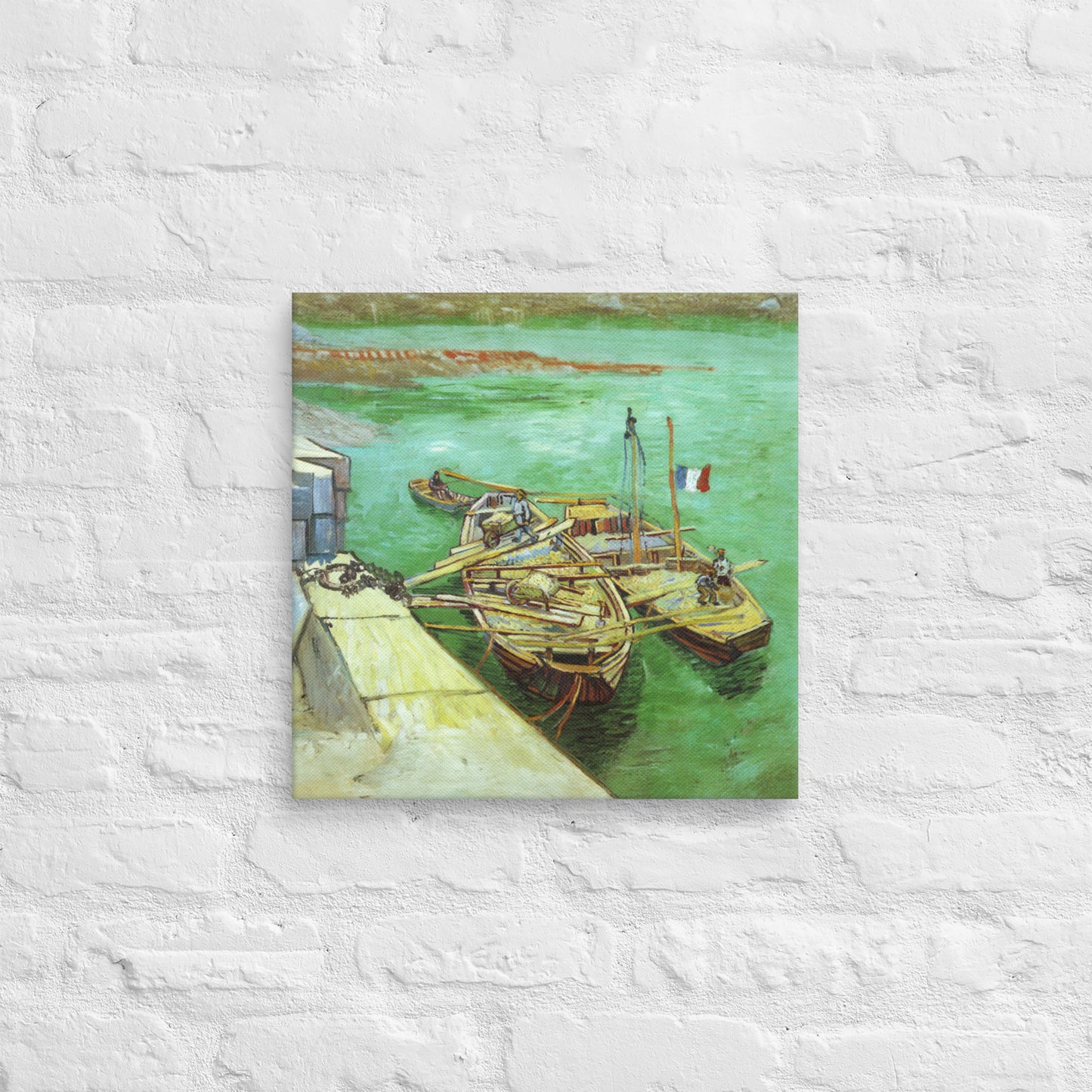 Van Gogh's 'Quay with Men Unloading Sand Barges' on a 16"x16" unframed canvas print on a white brick wall.