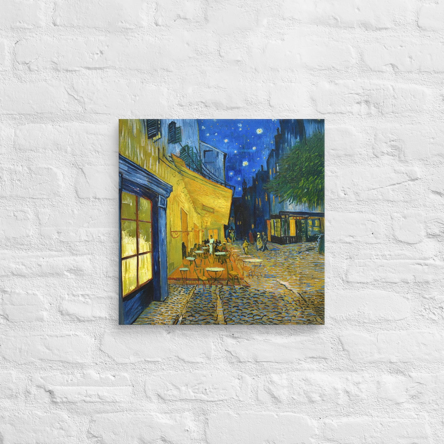 Van Gogh's 'Café Terrace at Night' on a 16"x16" unframed canvas print on a white brick wall.