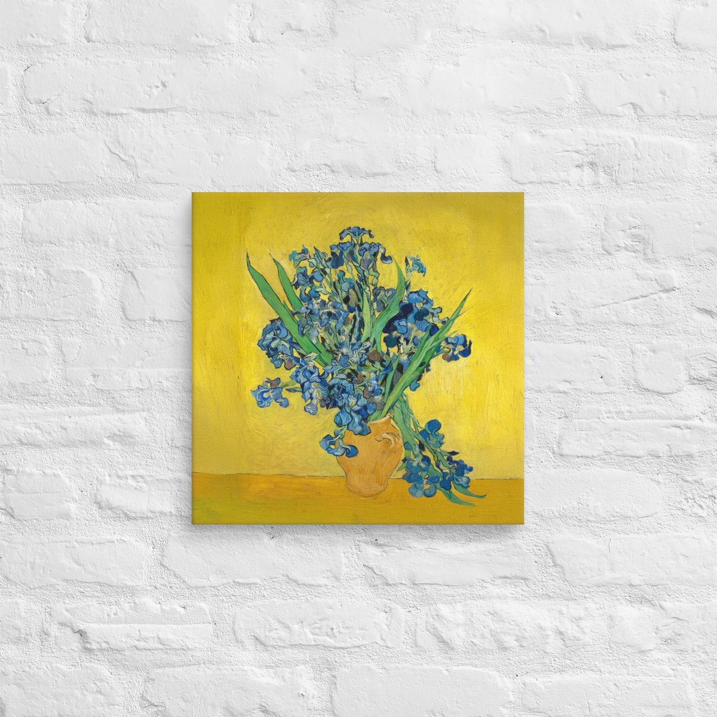 Van Gogh's 'Vase with Irises Against a Yellow Background' on a 16"x16" unframed canvas print on a white brick wall.