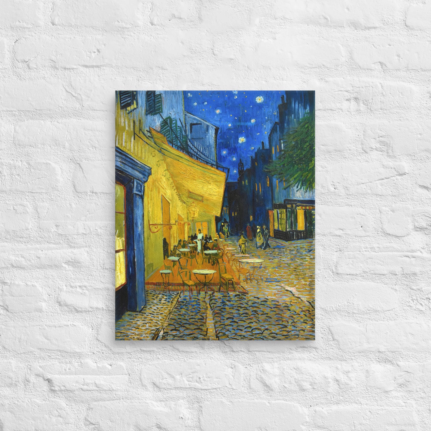 Van Gogh's 'Café Terrace at Night' on a 16"x20" unframed canvas print on a white brick wall.