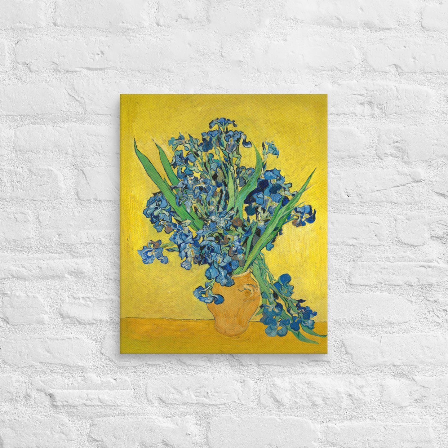 Van Gogh's 'Vase with Irises Against a Yellow Background' on a 16"x20" unframed canvas print on a white brick wall.