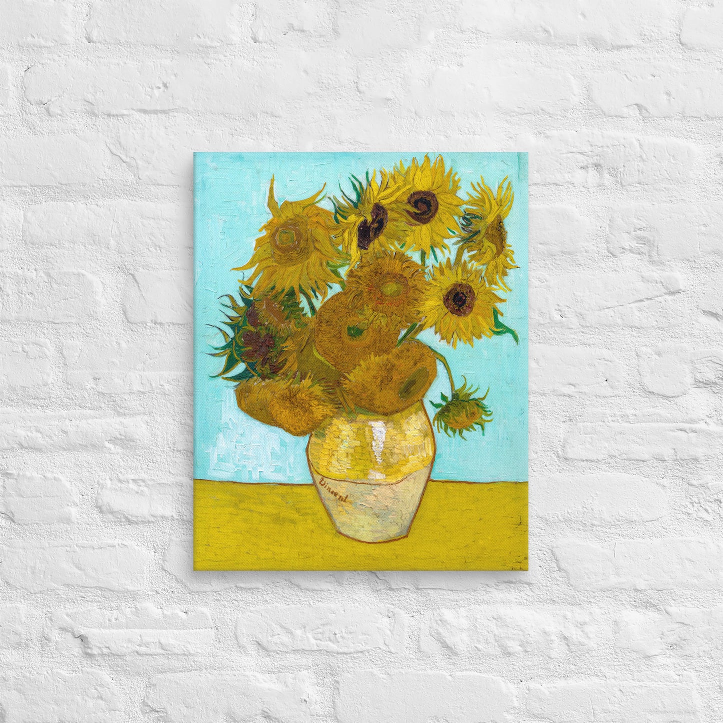 Van Gogh's 'Vase with Twelve Sunflowers' on a 16"x20" unframed canvas print on a white brick wall.