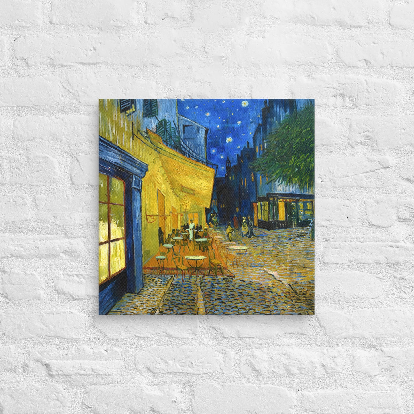 Van Gogh's 'Café Terrace at Night' on a 18"x18" unframed canvas print on a white brick wall.