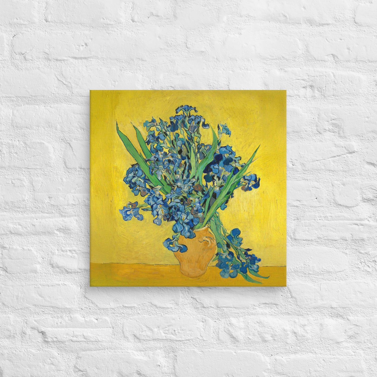 Van Gogh's 'Vase with Irises Against a Yellow Background' on a 18"x18" unframed canvas print on a white brick wall.