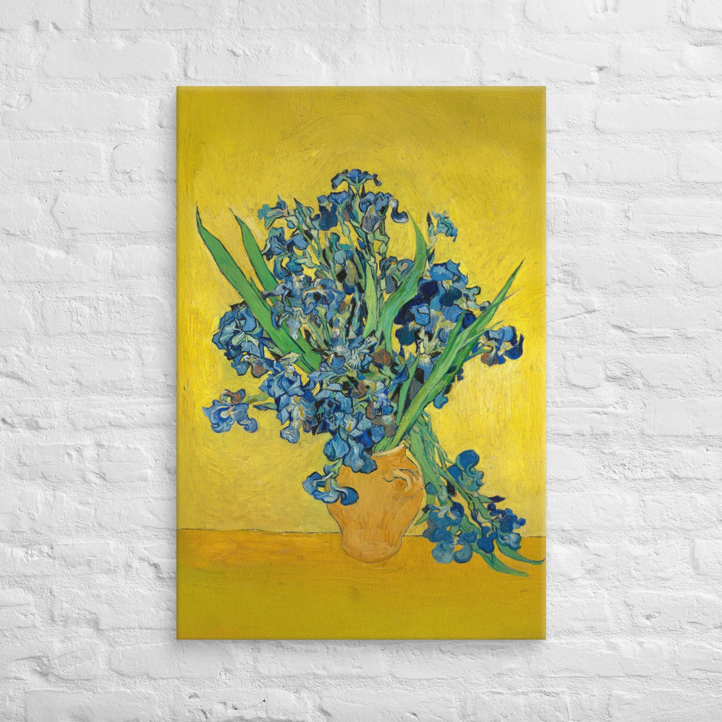 Van Gogh's 'Vase with Irises Against a Yellow Background' on a 24"x36" unframed canvas print on a white brick wall.