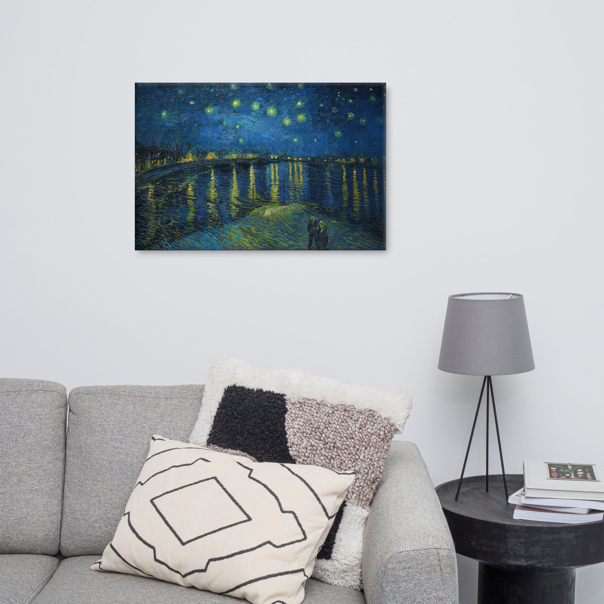 Van Gogh's 'Starry Night Over the Rhone' on a 24"x36" unframed canvas print on a white wall above a gray sofa with throw pillows and side table with a lamp.