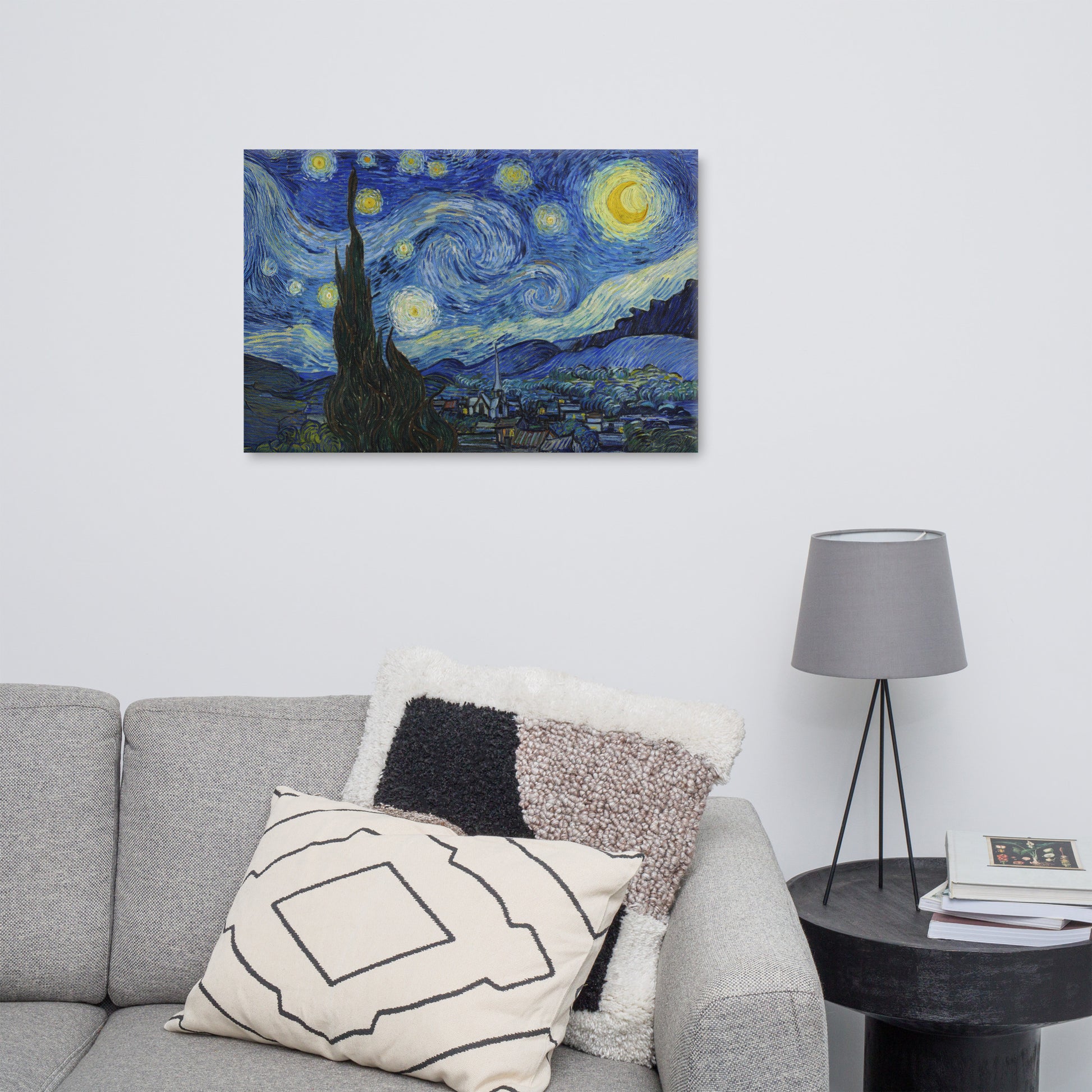 Van Gogh's 'Starry Night' on a 24"x36" unframed canvas print on a white wall above a gray sofa with throw pillows and side table with a lamp.