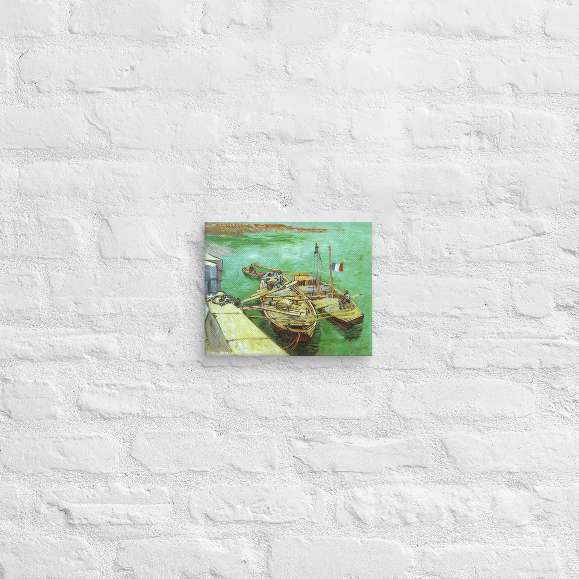 Van Gogh's 'Quay with Men Unloading Sand Barges' on a 8"x10" unframed canvas print on a white brick wall.