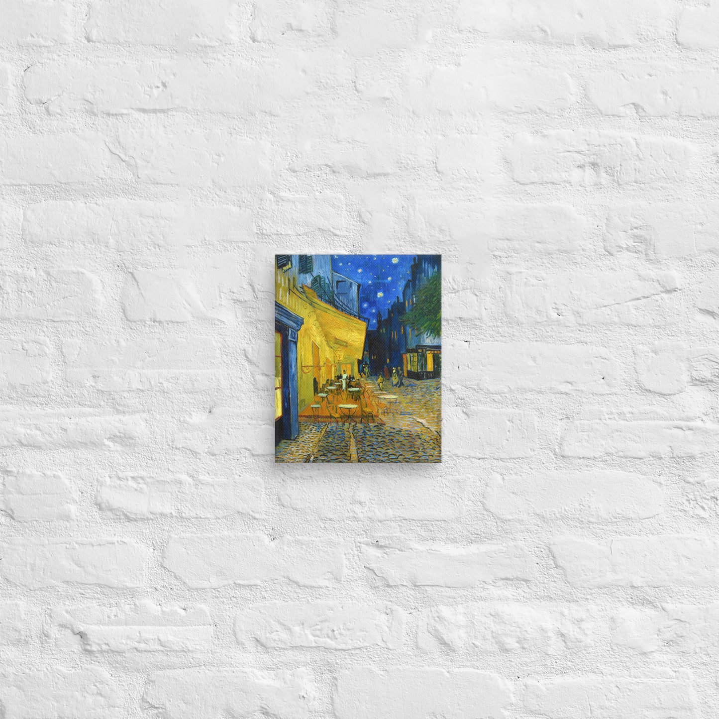 Van Gogh's 'Café Terrace at Night' on a 8"x10" unframed canvas print on a white brick wall.