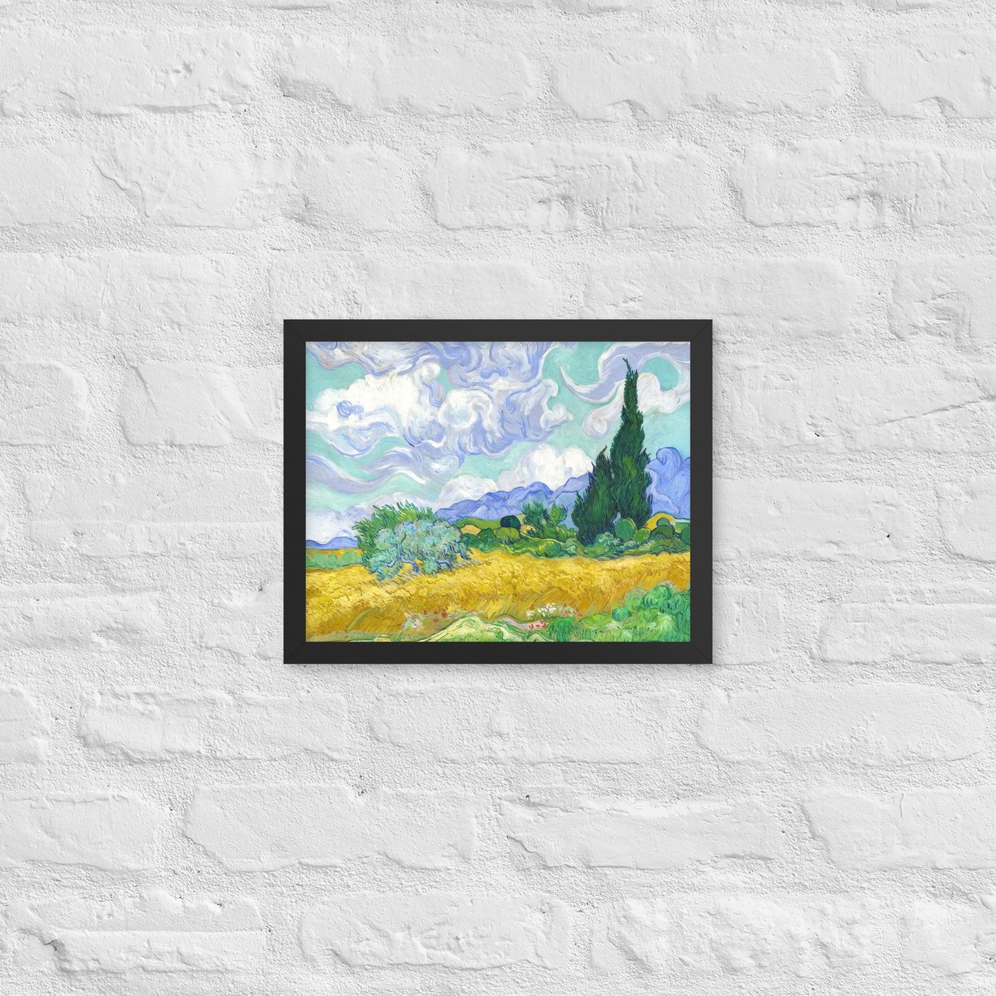 Van Gogh's 'Wheat Field with Cypresses' on a 11"x14" black framed poster print on a white brick wall.