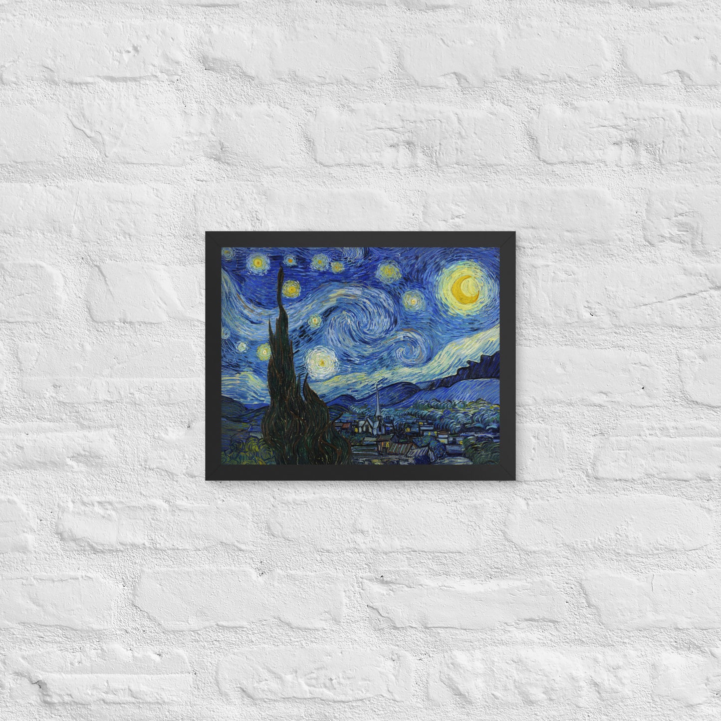 Van Gogh's 'Starry Night' on a 11"x14" black framed poster print on a white brick wall.
