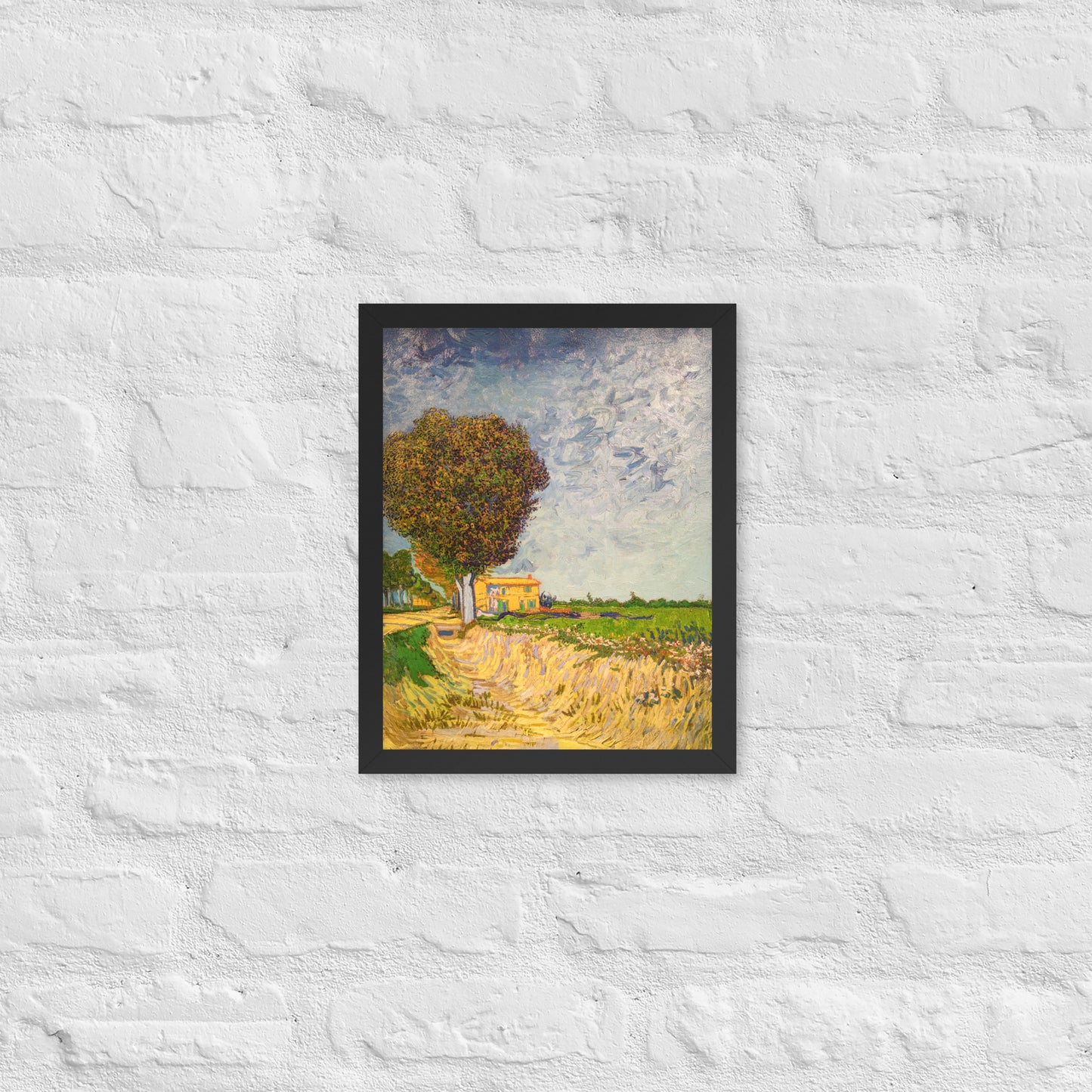 Van Gogh's 'A Lane near Arles' on a 11"x14" black framed poster print on a white brick wall.