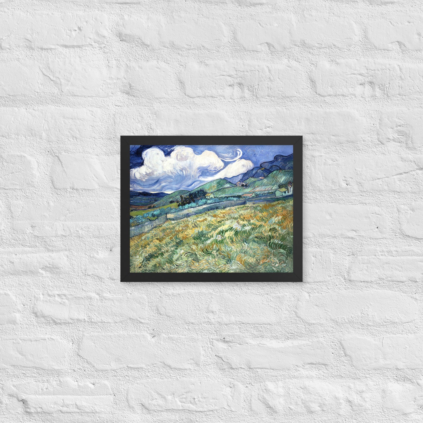Van Gogh's 'Landscape from Saint-Rémy' on a 11"x14" black framed poster print on a white brick wall.