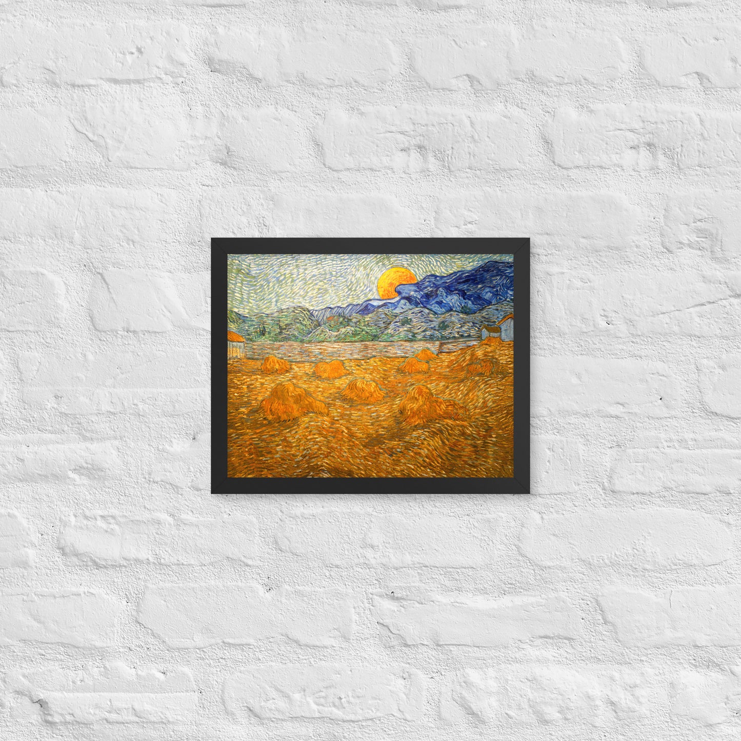 Van Gogh's 'Landscape with Wheat Sheaves and Rising Moon' on a 11"x14" black framed poster print on a white brick wall.