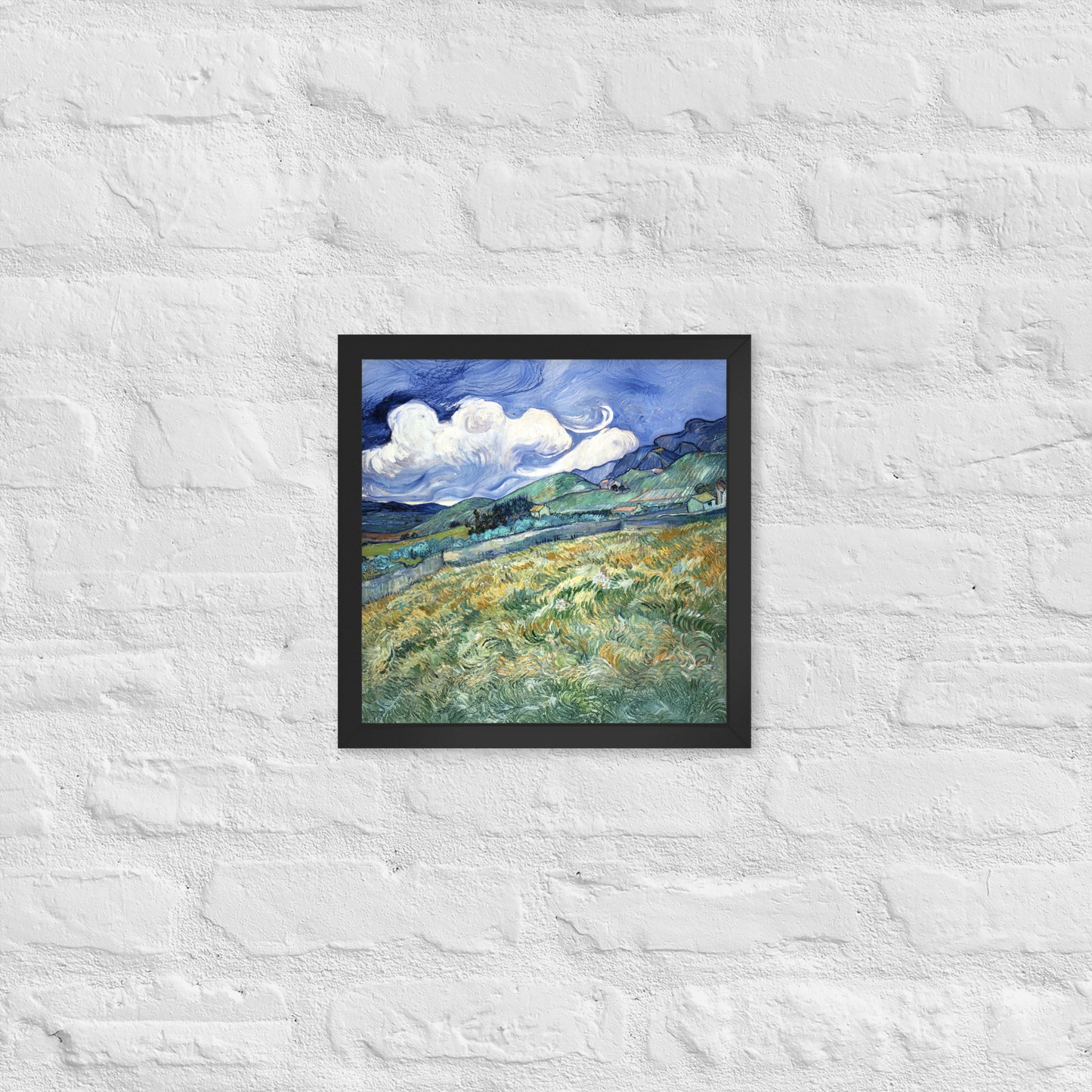 Van Gogh's 'Landscape from Saint-Rémy' on a 12"x12" black framed poster print on a white brick wall.