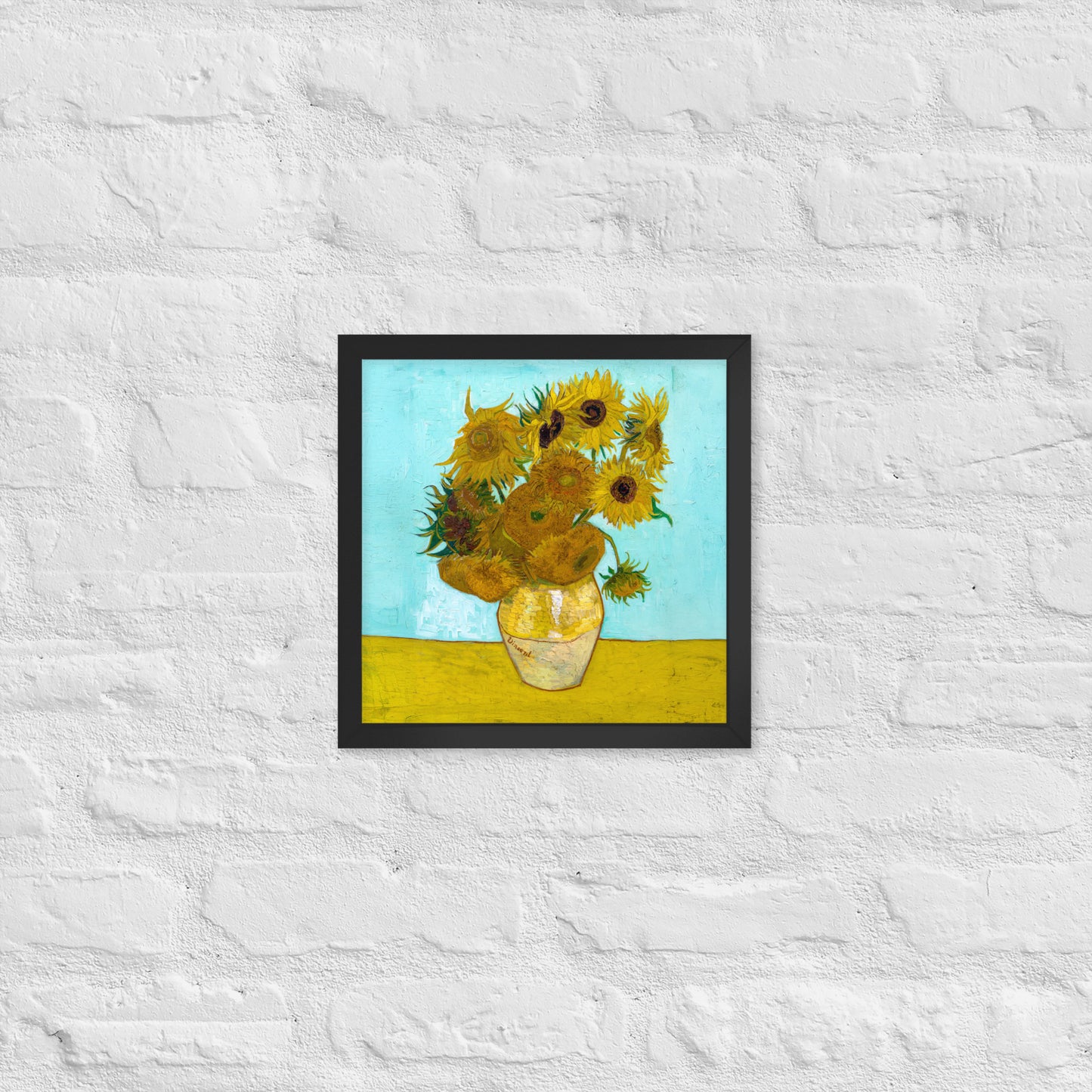 Van Gogh's 'Vase with Twelve Sunflowers' on a 12"x12" black framed poster print on a white brick wall.