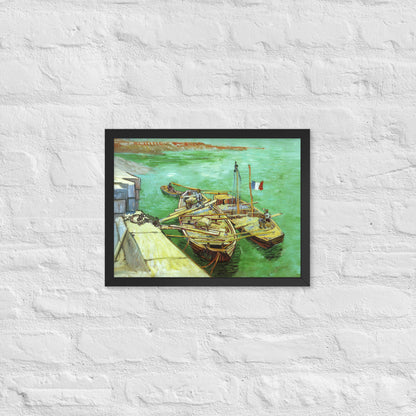 Van Gogh's 'Quay with Men Unloading Sand Barges' on a 12"x16" black framed poster print on a white brick wall.