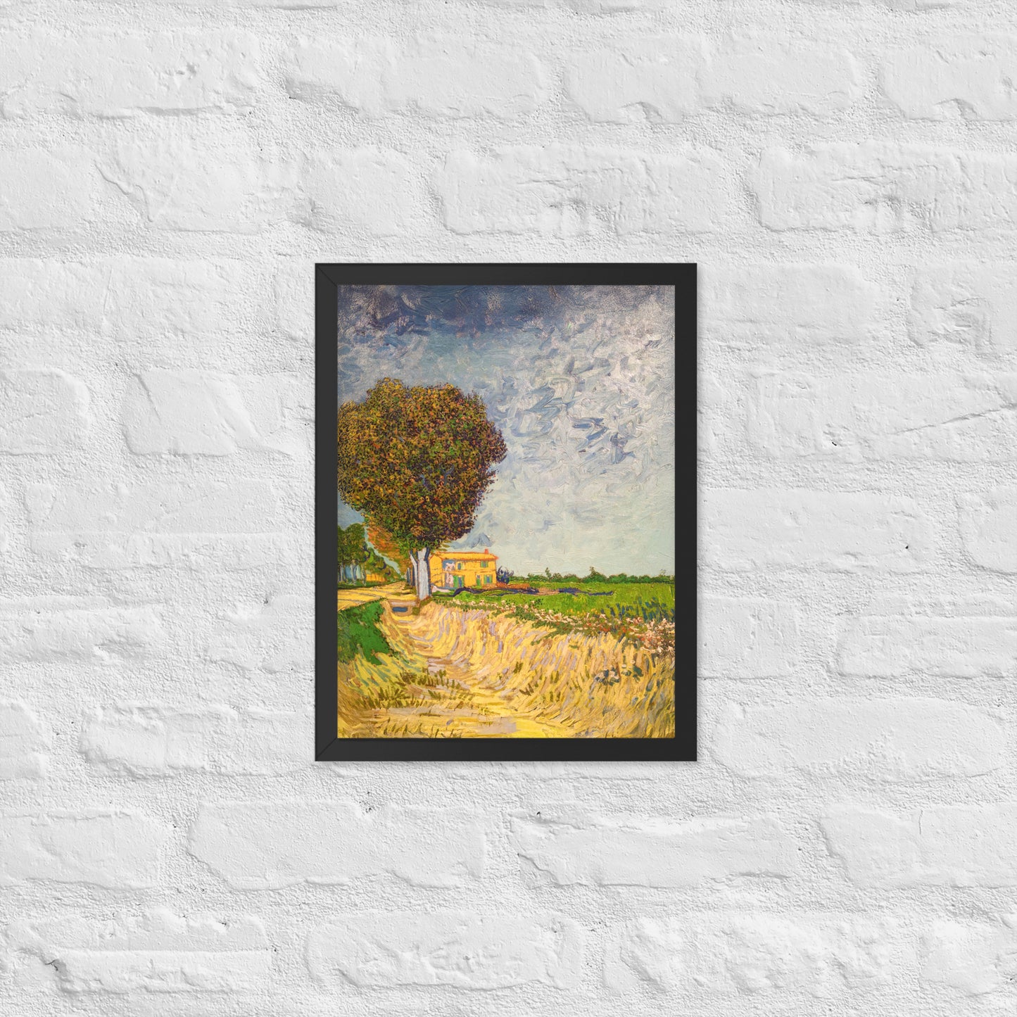Van Gogh's 'A Lane near Arles' on a 12"x16" black framed poster print on a white brick wall.