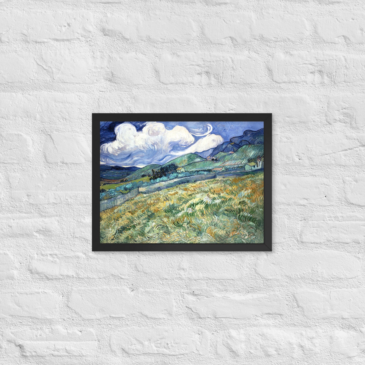 Van Gogh's 'Landscape from Saint-Rémy' on a 12"x16" black framed poster print on a white brick wall.