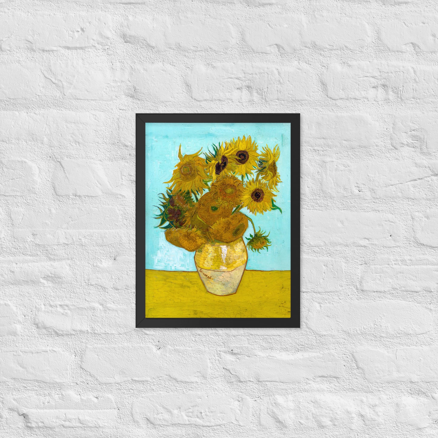 Van Gogh's 'Vase with Twelve Sunflowers' on a 12"x16" black framed poster print on a white brick wall.