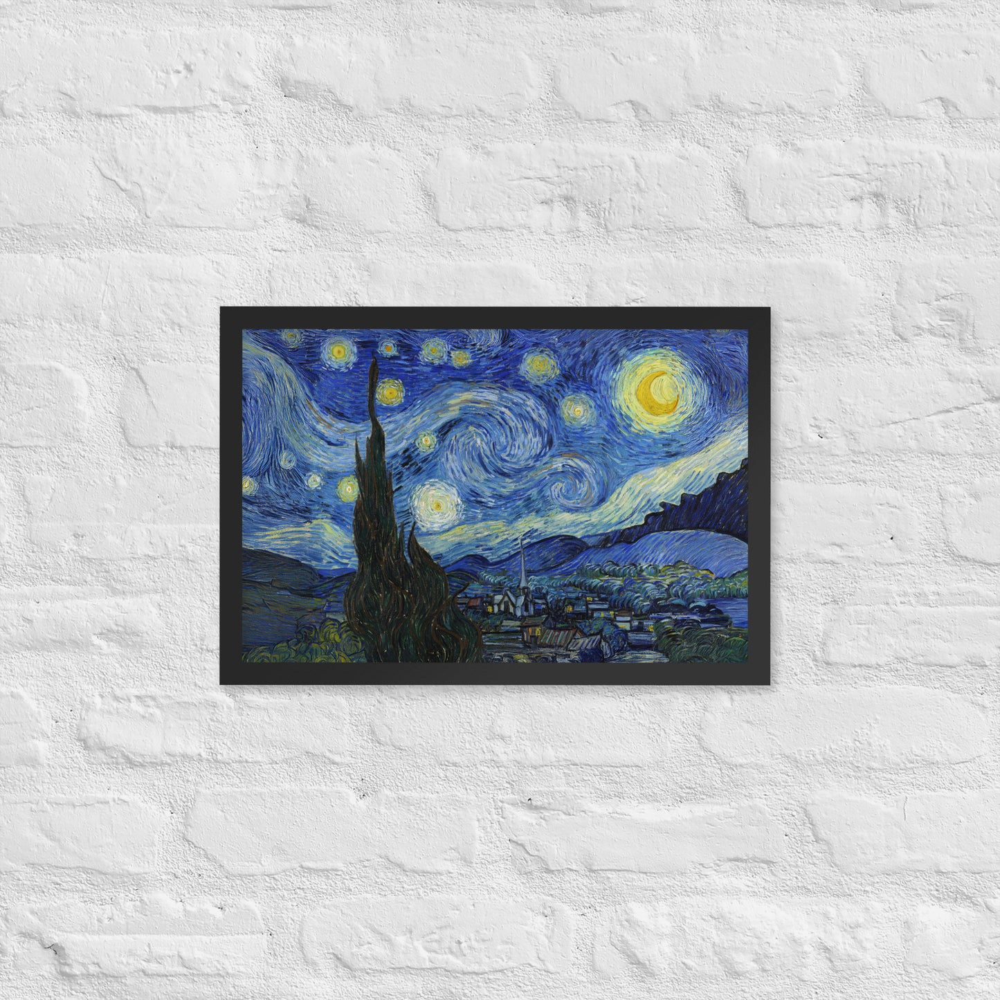 Van Gogh's 'Starry Night' on a 12"x18" black framed poster print on a white brick wall.